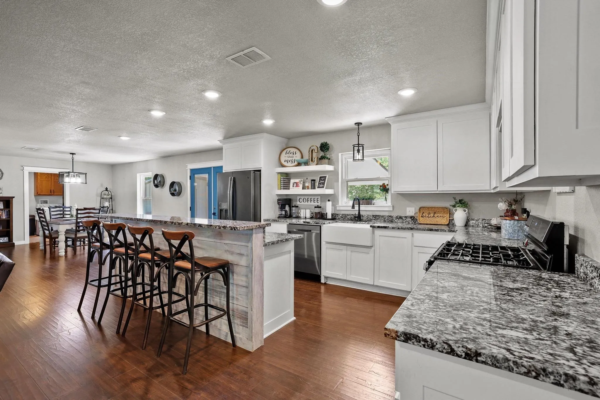 Kitchen featuring white shaker cabinetry, speckled countertops, stainless steel appliances, and a farmhouse sink