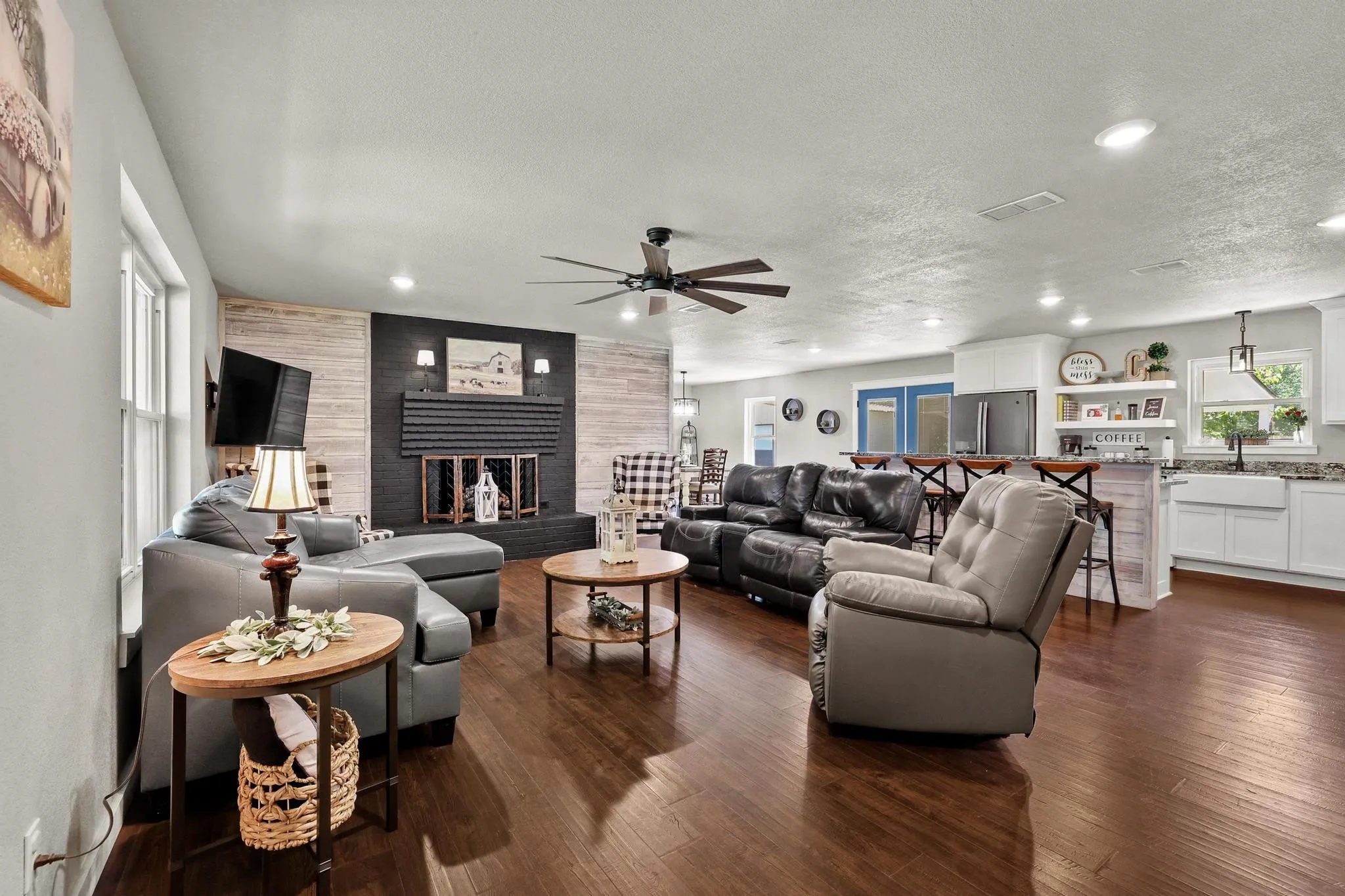 Spacious open-concept living area featuring dark wood-finish flooring, a contemporary ceiling fan, and recessed lighting
