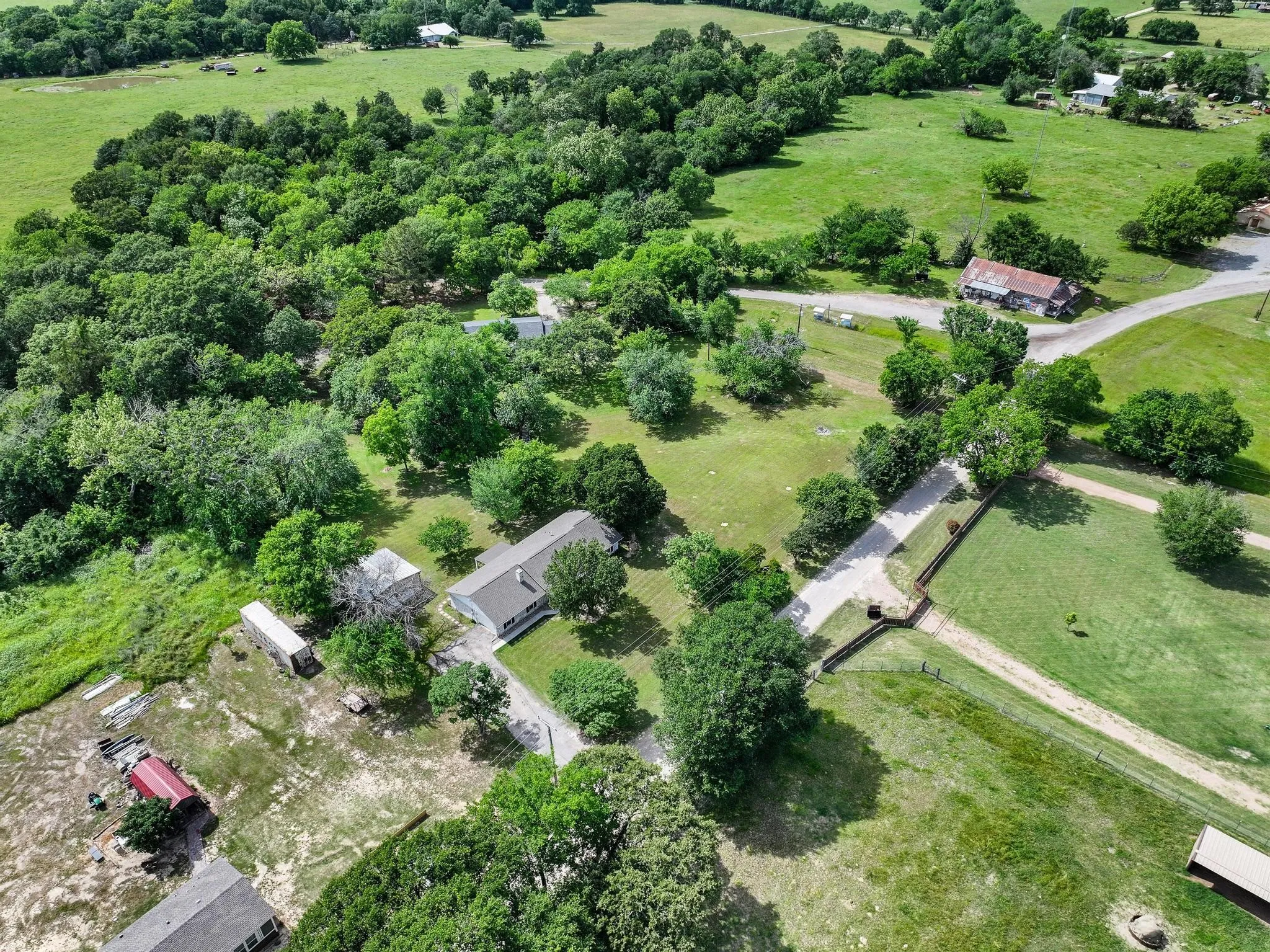 Expansive property featuring verdant fields, mature trees, and multiple structures