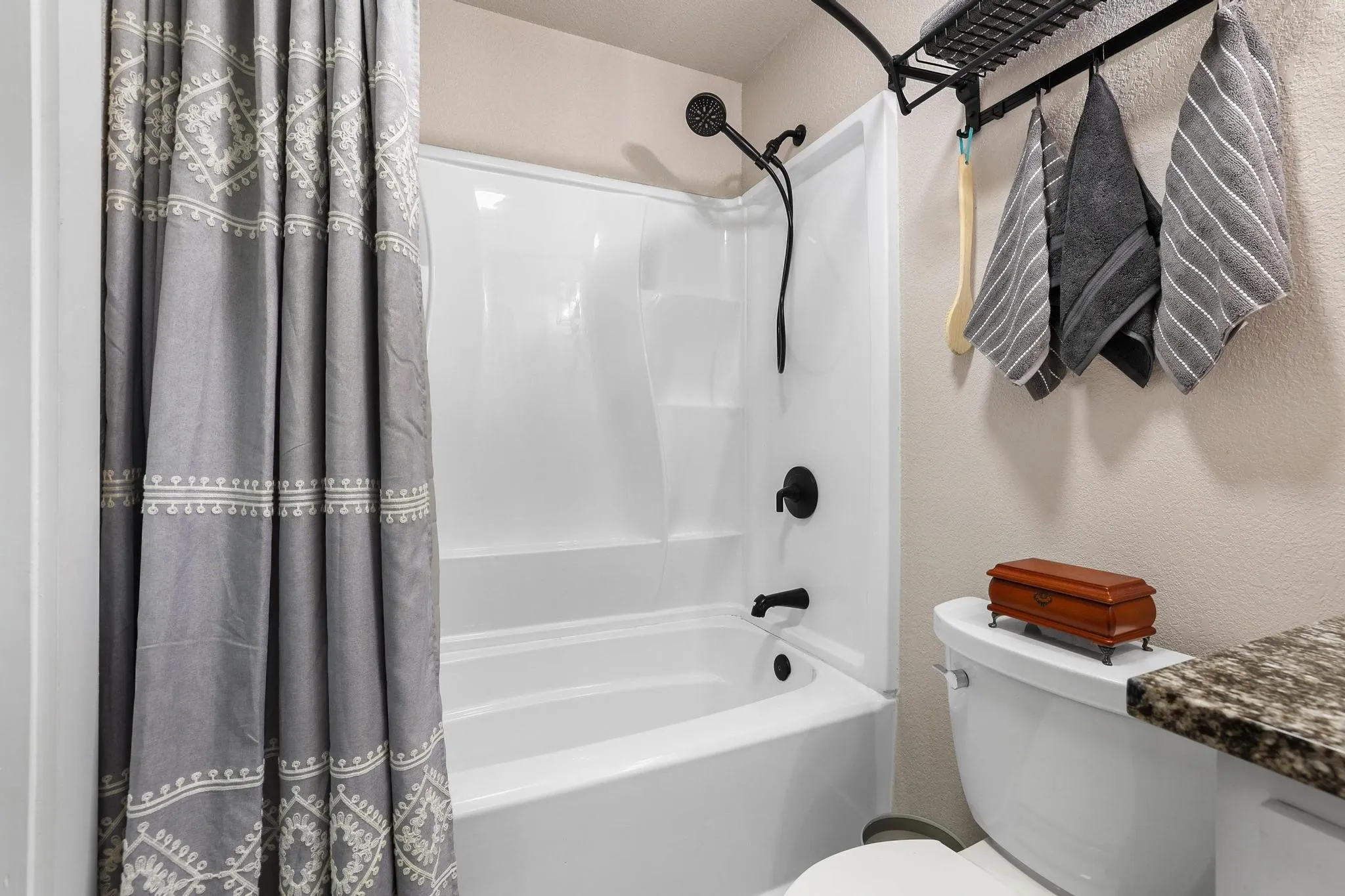 White fiberglass tub and shower combination with matte black fixtures