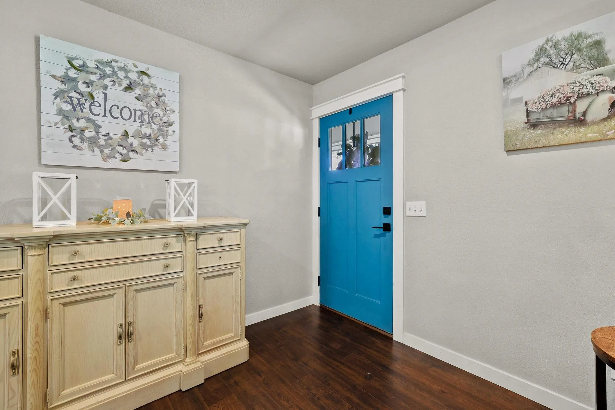 Entryway featuring a bright blue door with upper window panes, dark wood-finish flooring, and white trim
