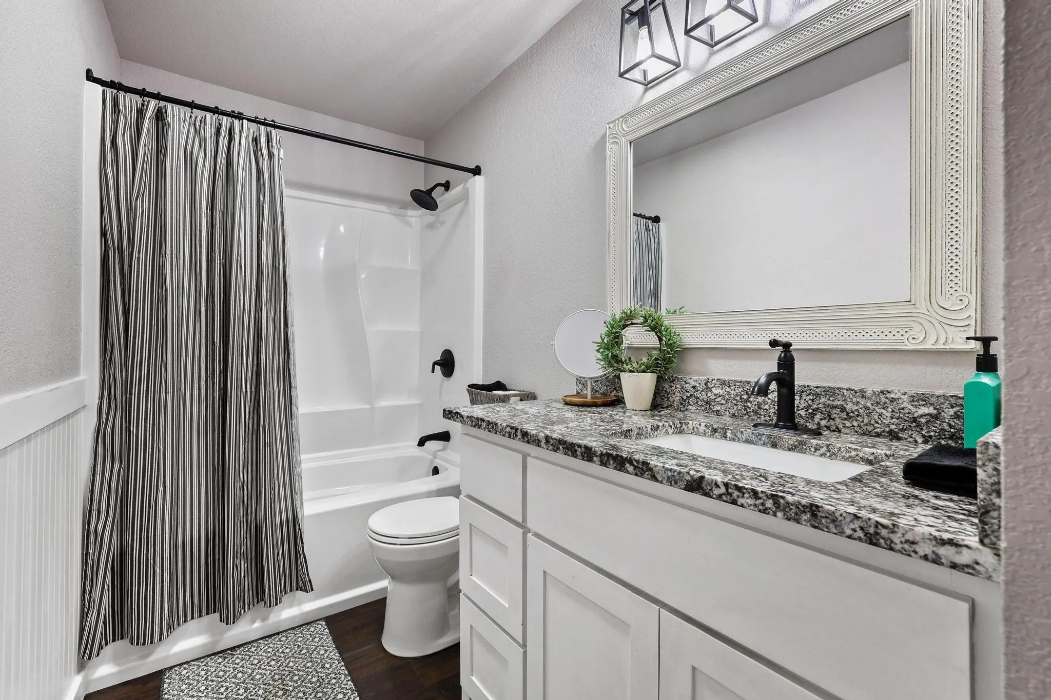 Bathroom featuring a single vanity with stone-finish countertop, undermount sink, and matte black faucet