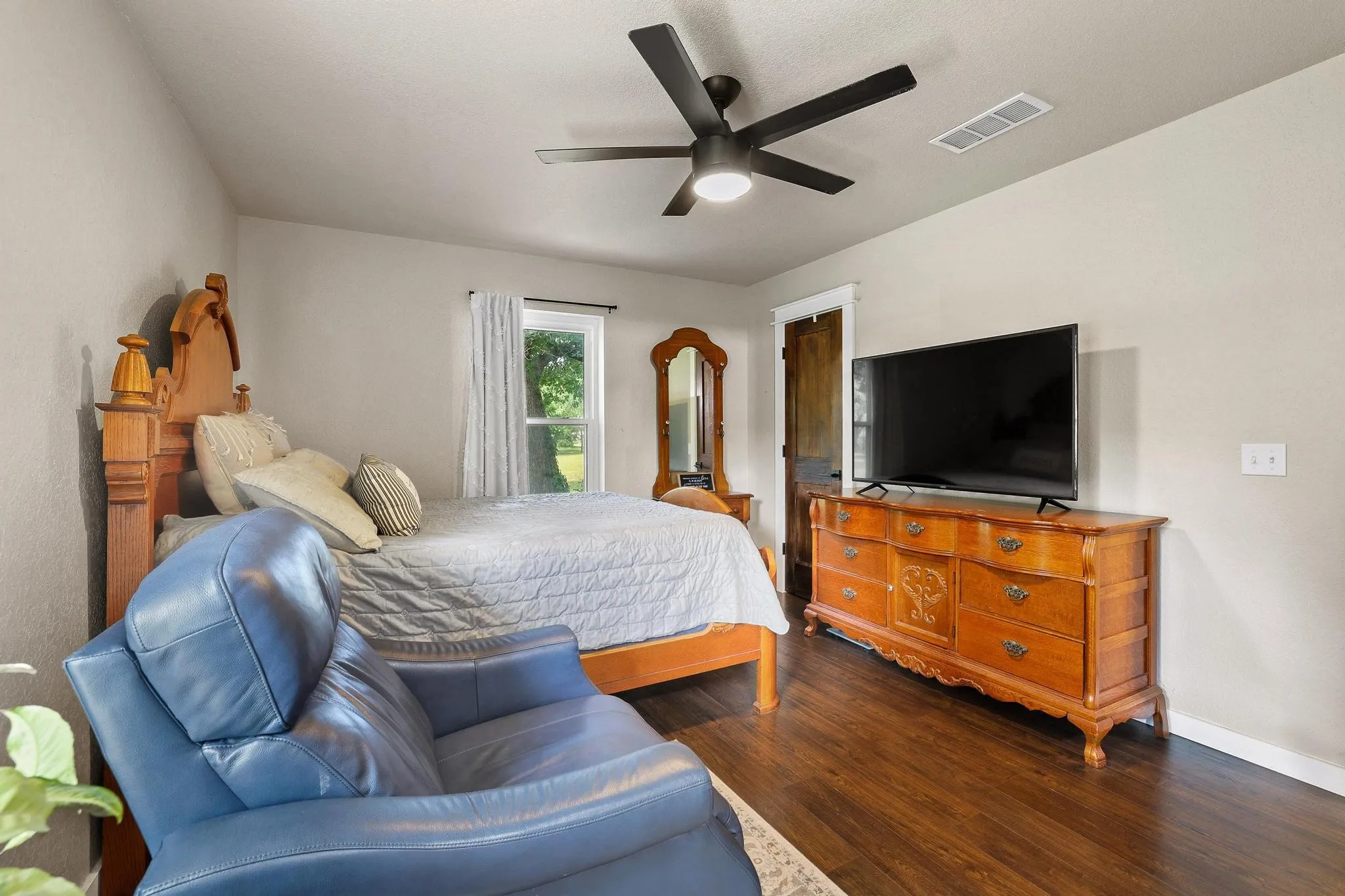Spacious room featuring wood-finish flooring, a window with exterior views, and a ceiling fan with integrated lighting