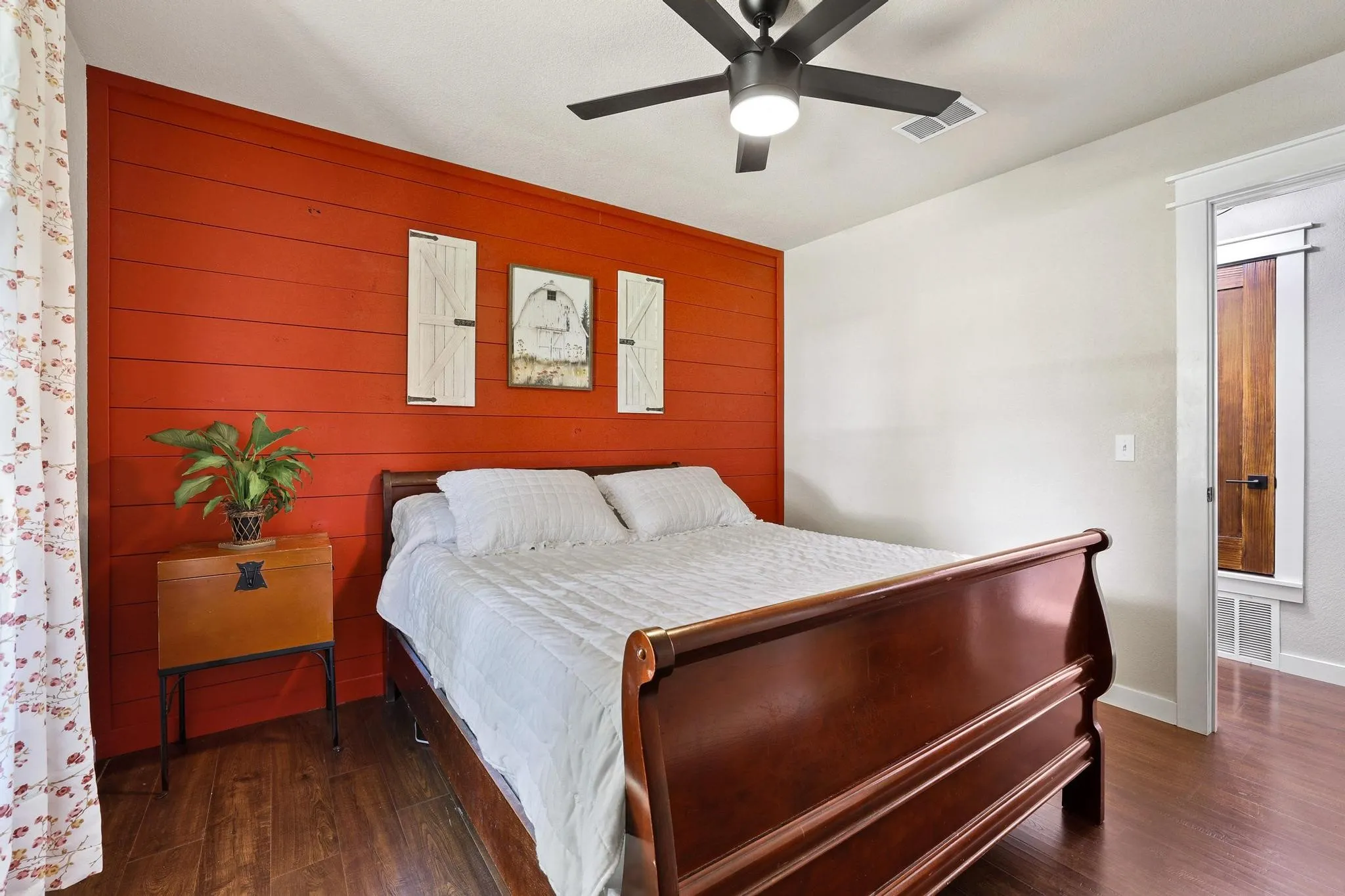 Bedroom featuring a red shiplap accent wall and wood-finish flooring
