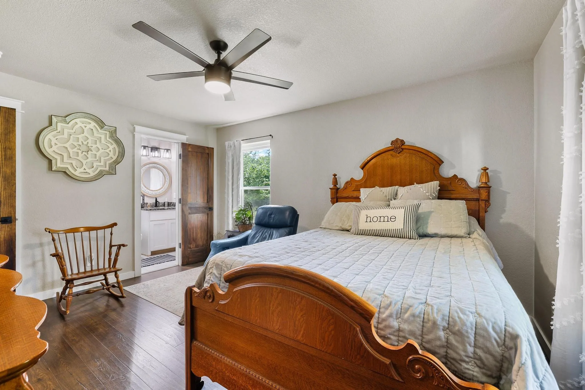 Bedroom featuring rich wood-finish flooring, a ceiling fan with integrated lighting, and a window with exterior views