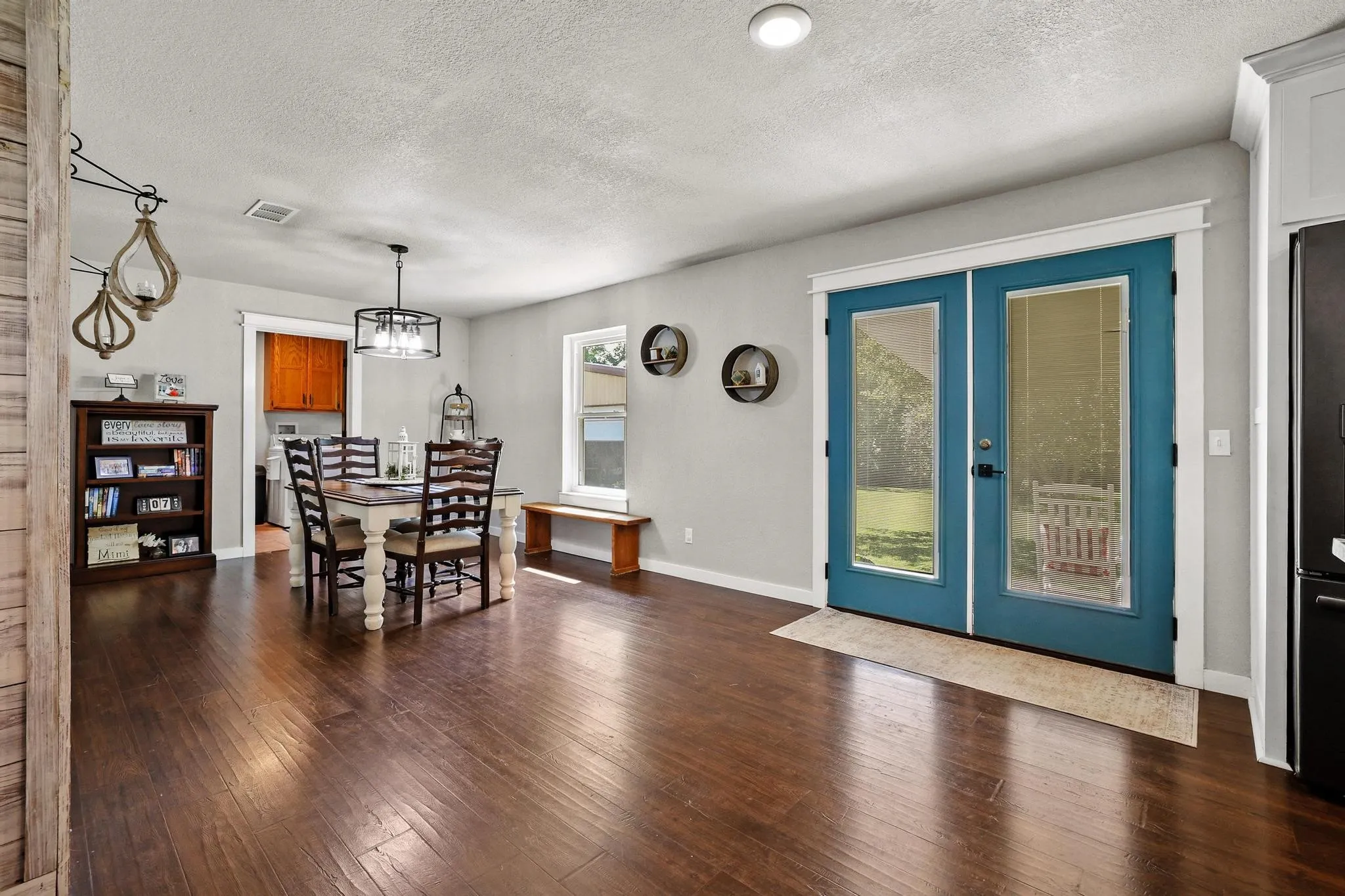 Spacious room featuring wood-finish flooring, a contemporary chandelier, recessed lighting, and bright blue French doors