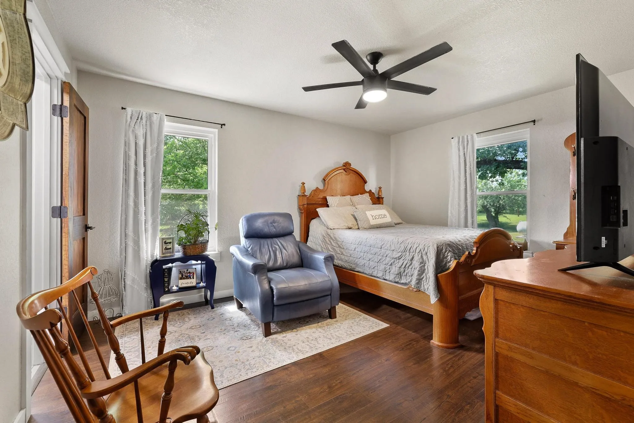Bedroom featuring wood-finish flooring, a contemporary ceiling fan with integrated lighting, and multiple windows