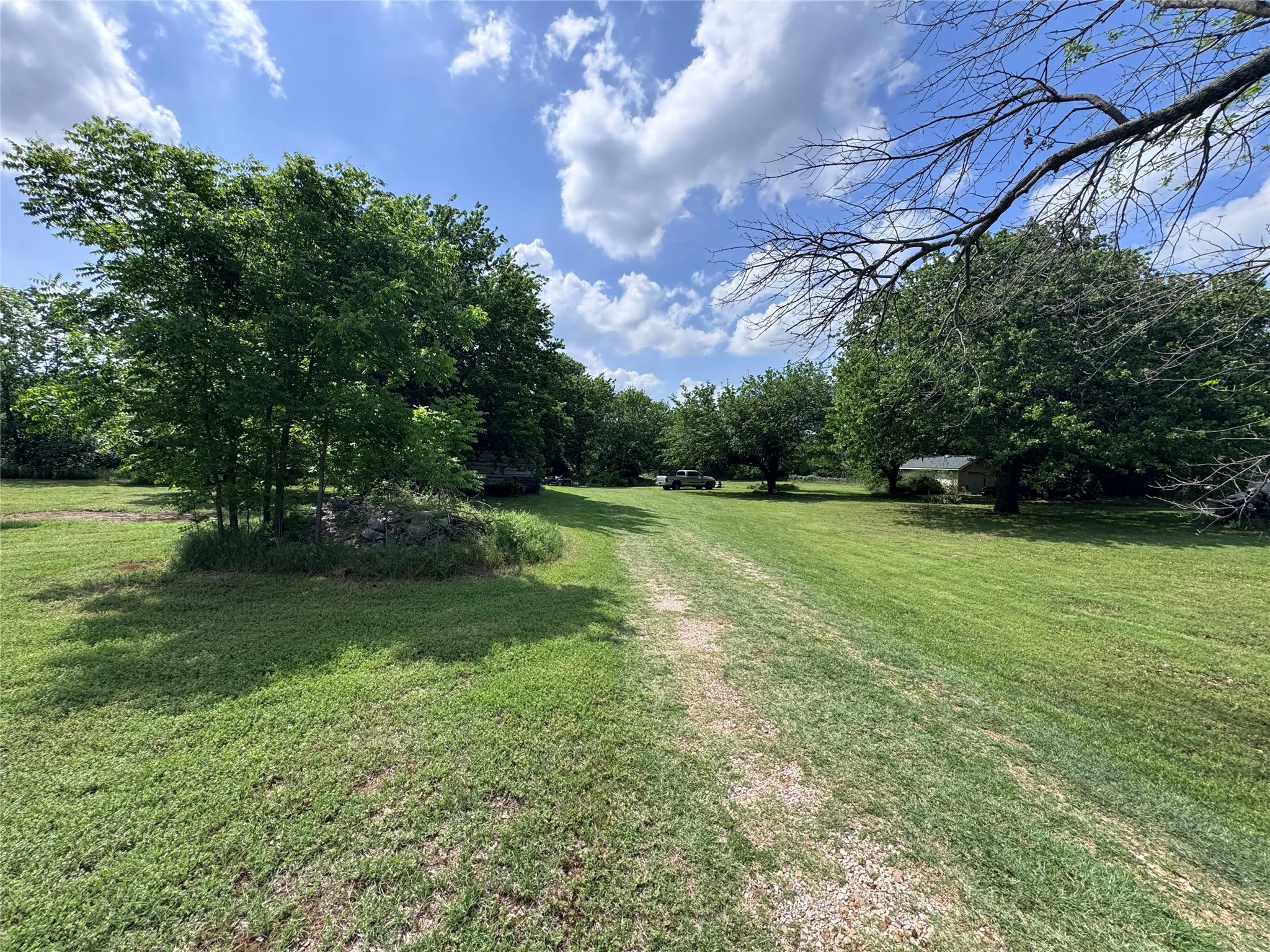 Expansive grassy area featuring a gravel path and mature trees