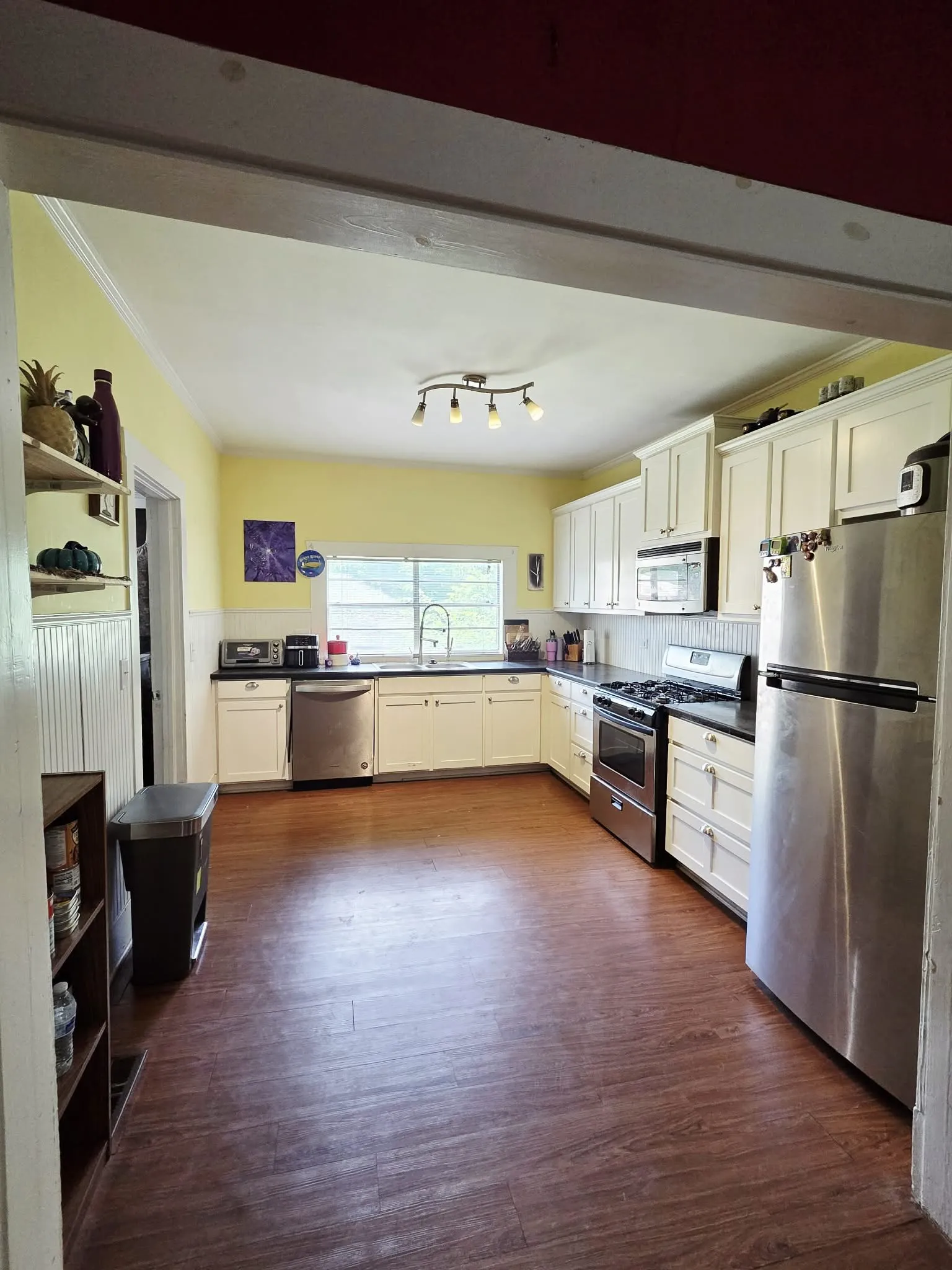 Kitchen featuring wood-finish flooring, white cabinetry, dark countertops, and stainless steel appliances
