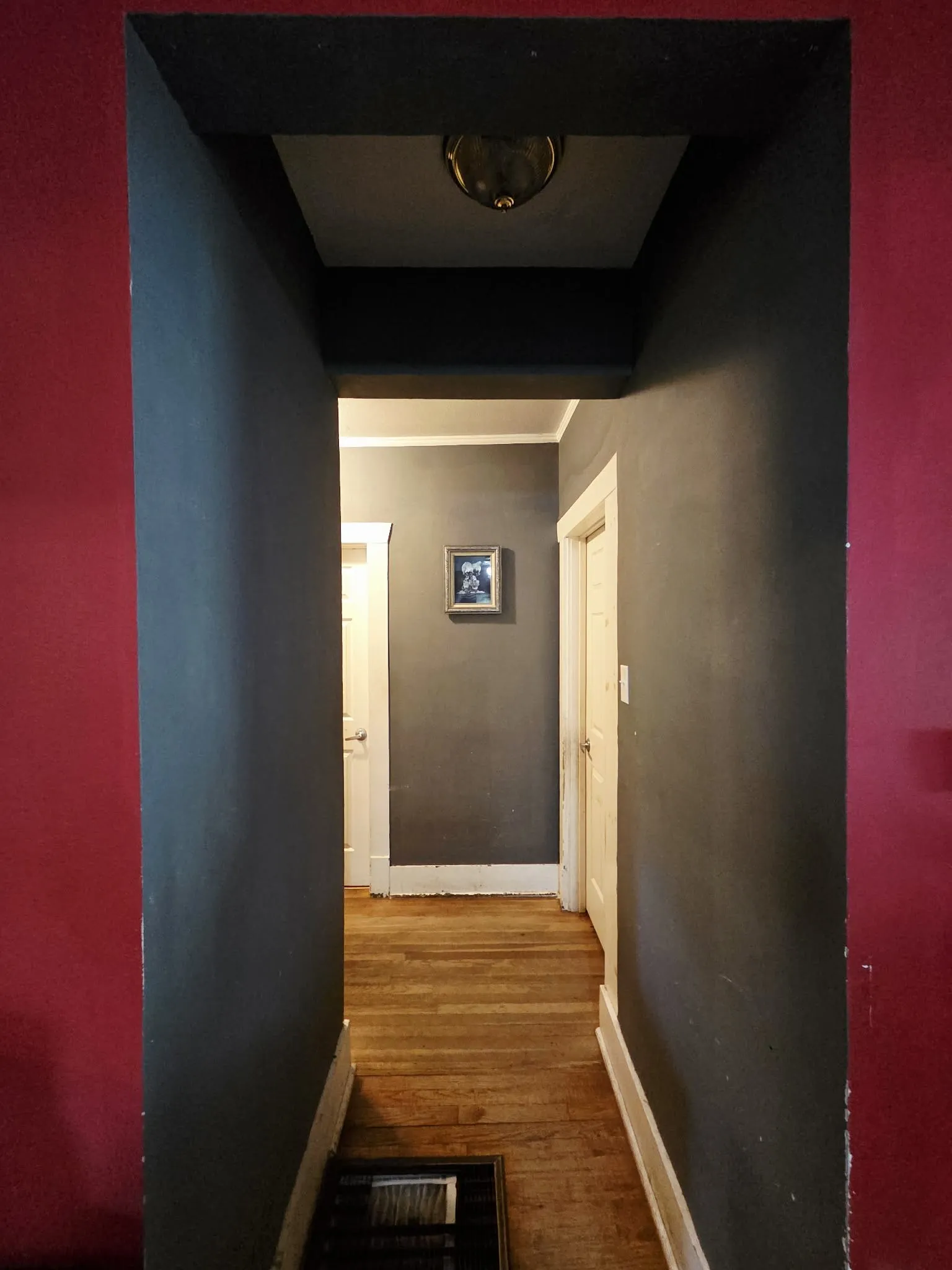 Hallway with wood-finish flooring, white baseboards, and a flush-mount ceiling light fixture