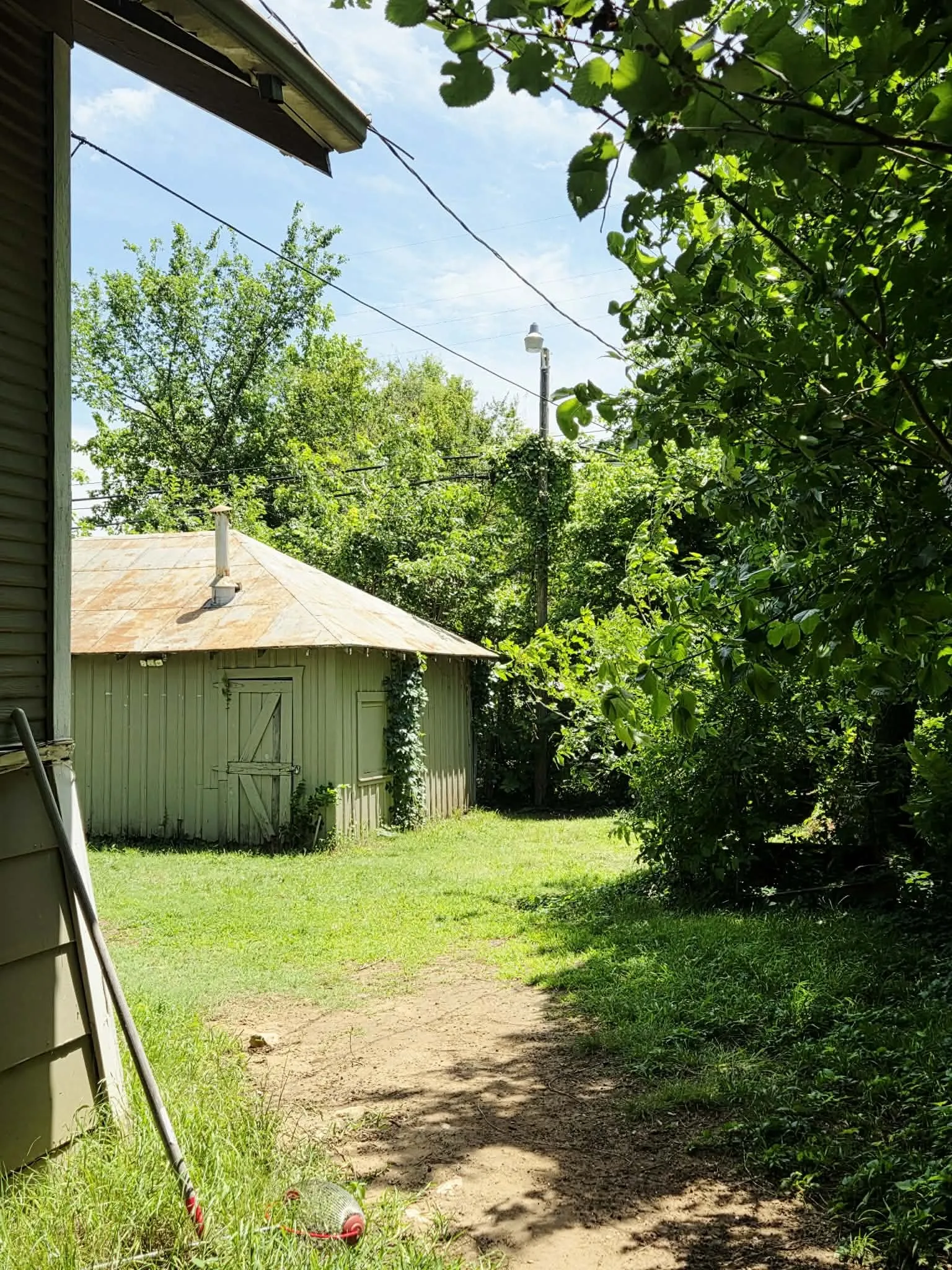 Detached shed structure featuring vertical siding and a sloped metal roof with a chimney vent