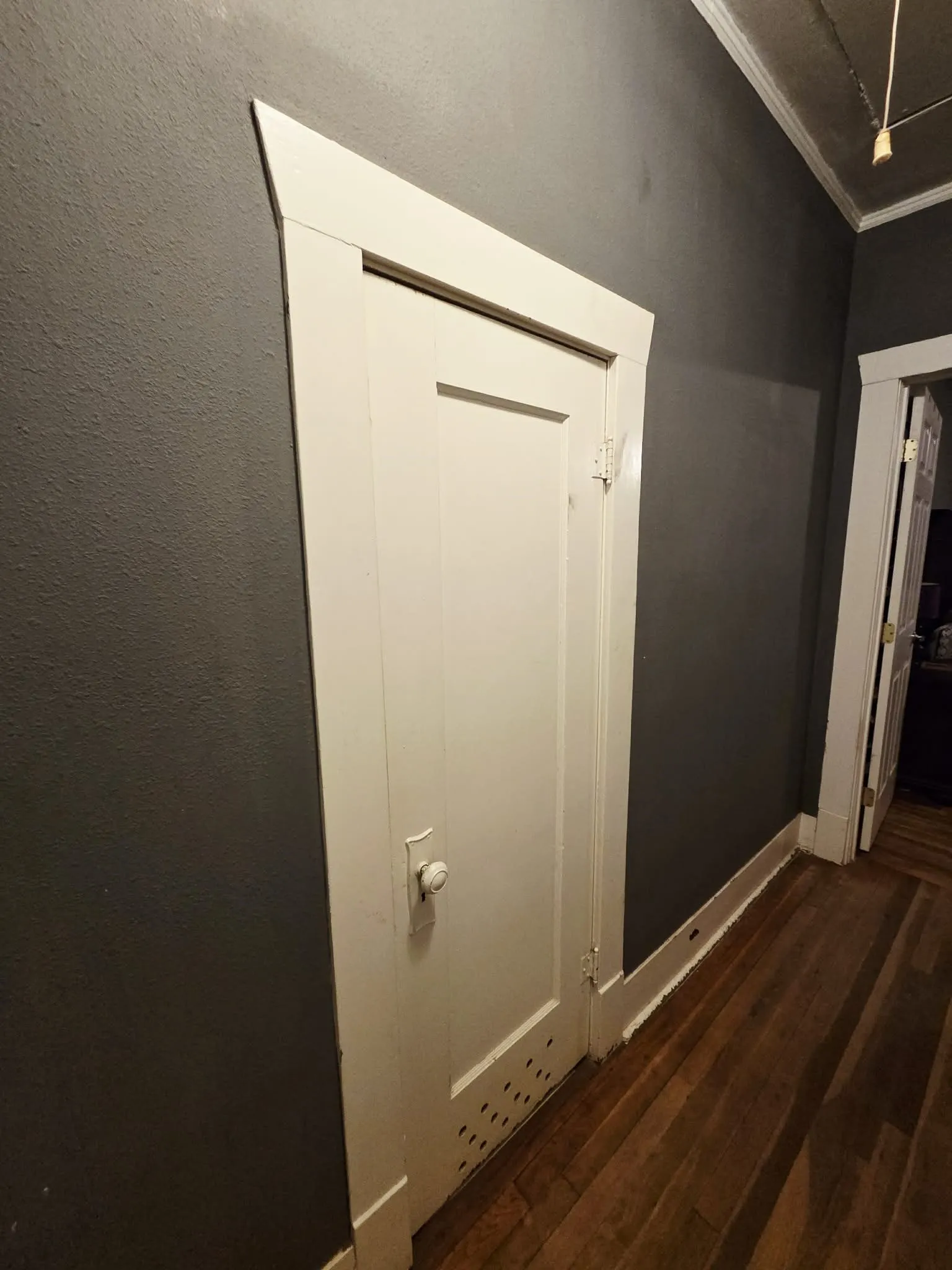White paneled door with traditional knob hardware and baseboard trim