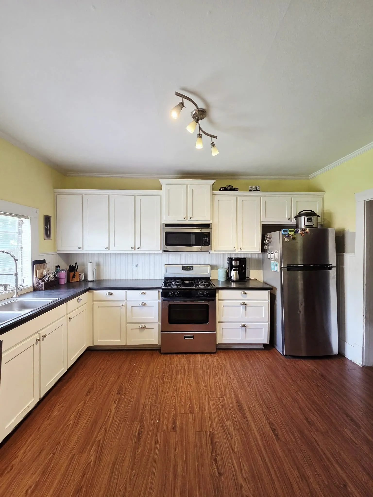 Kitchen featuring wood-finish flooring, white cabinetry, dark countertops, and a stainless steel appliance suite