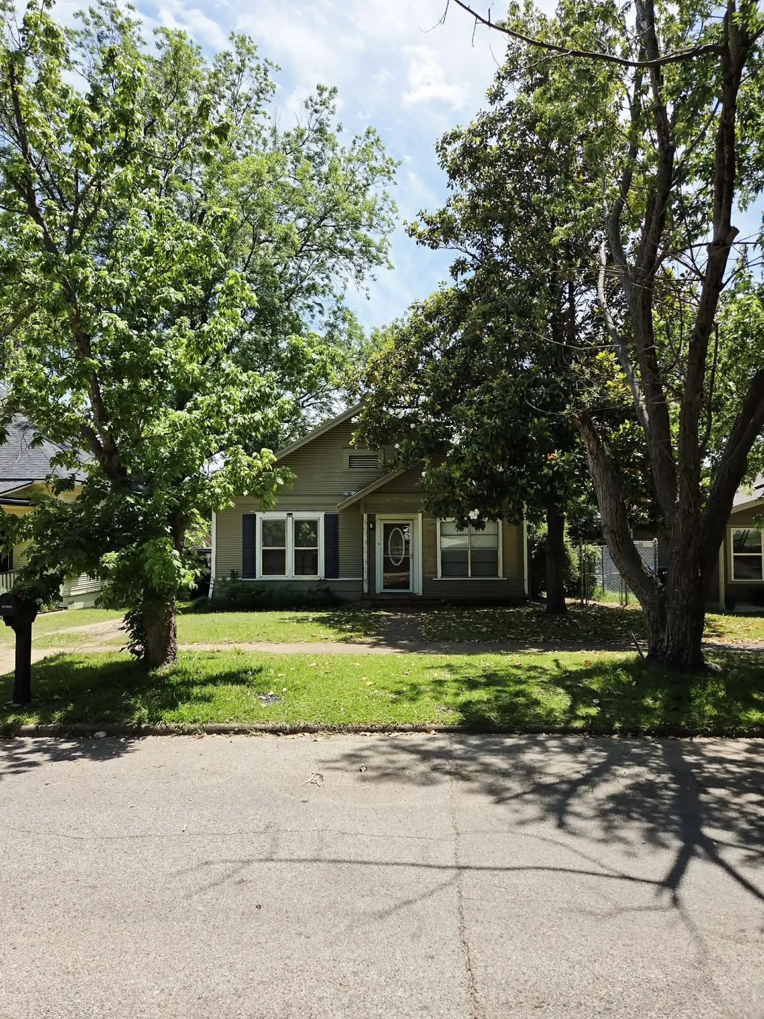 Single-story residential property featuring a neutral-toned exterior, dark shutters, and a front entry door with an oval glass insert