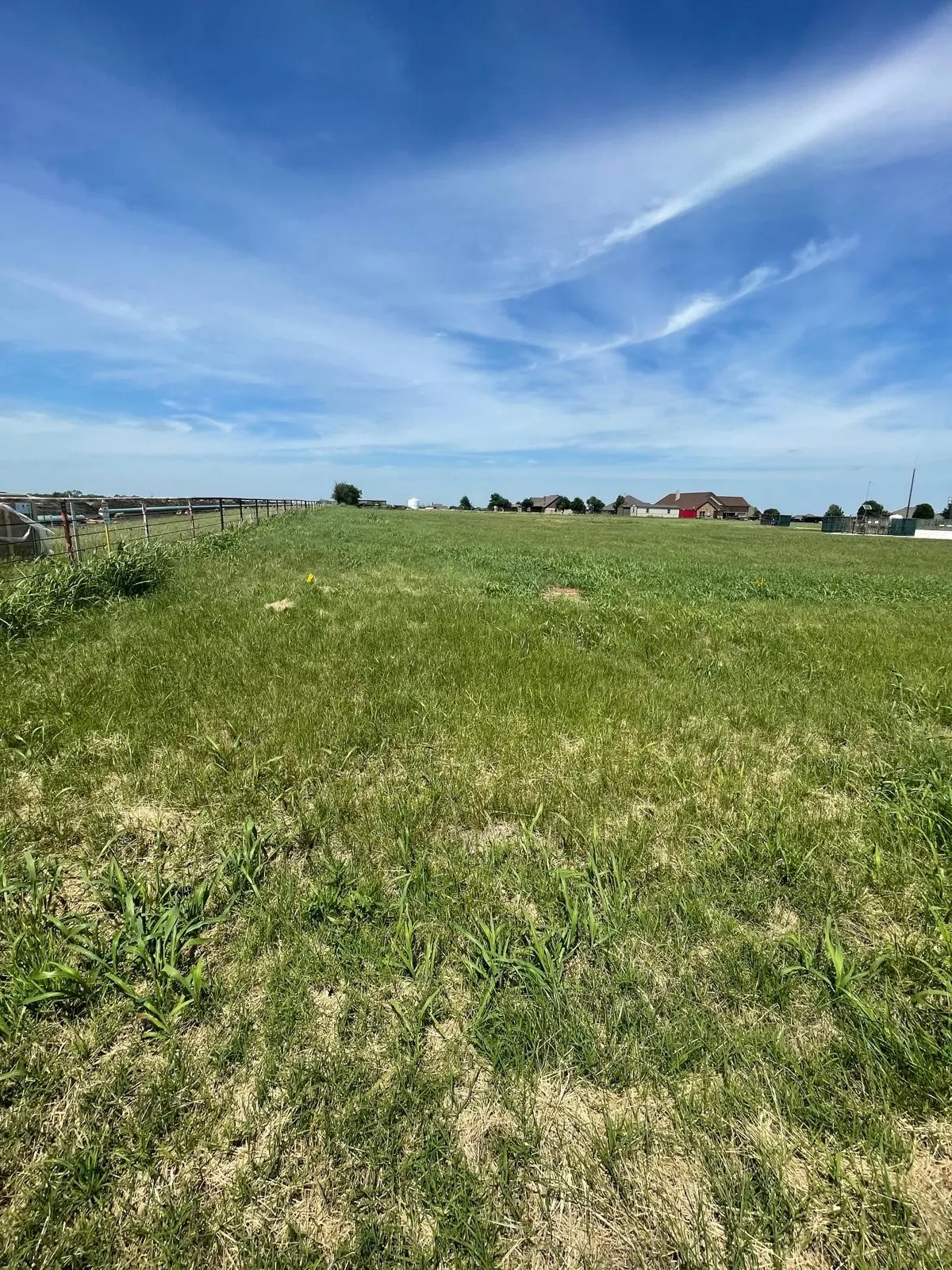 Expansive open lot featuring natural grassland and a perimeter fence