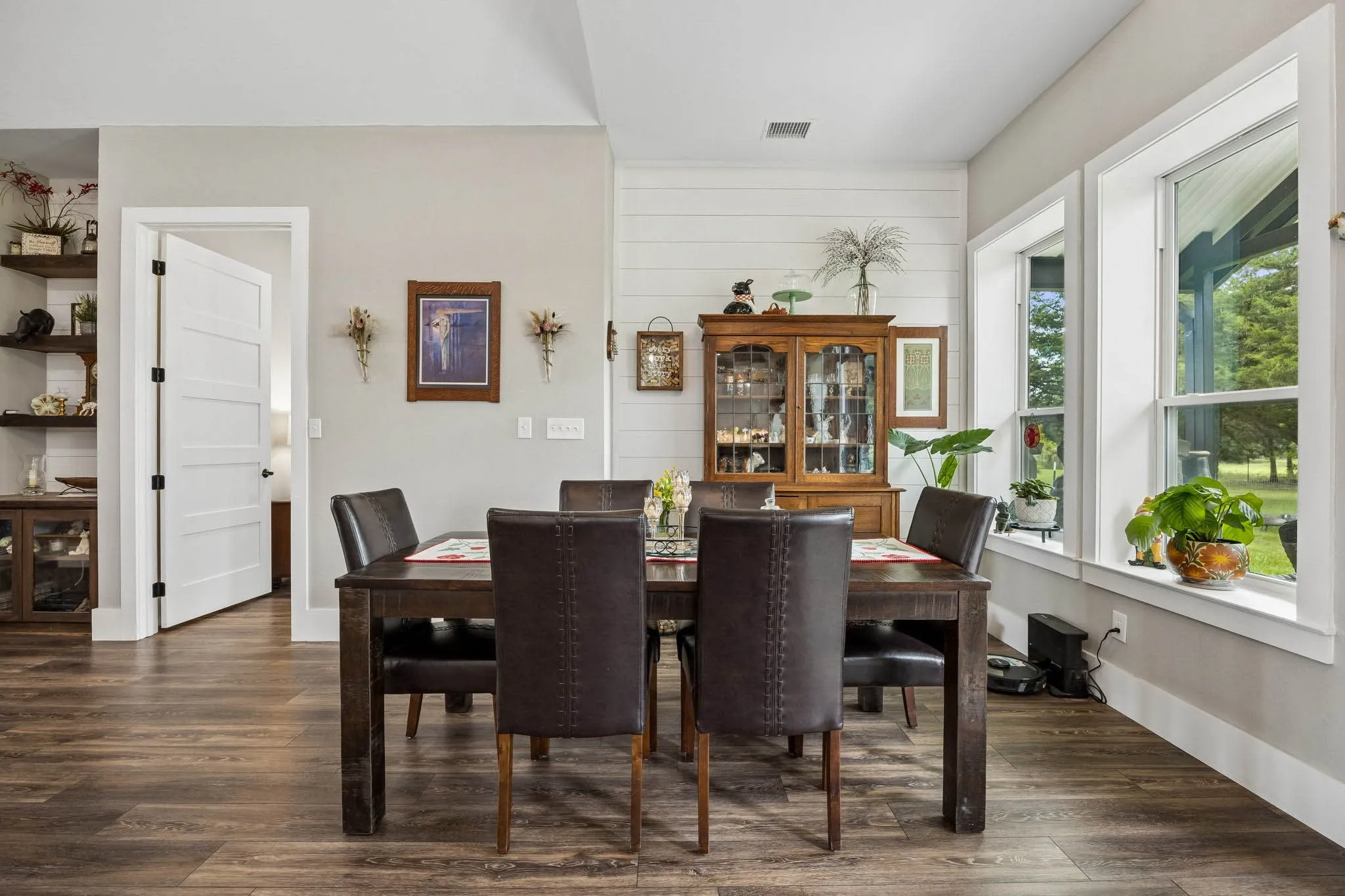 Dining area featuring wood-finish flooring, white shiplap accent wall, white trim, and ample natural light from multiple windows