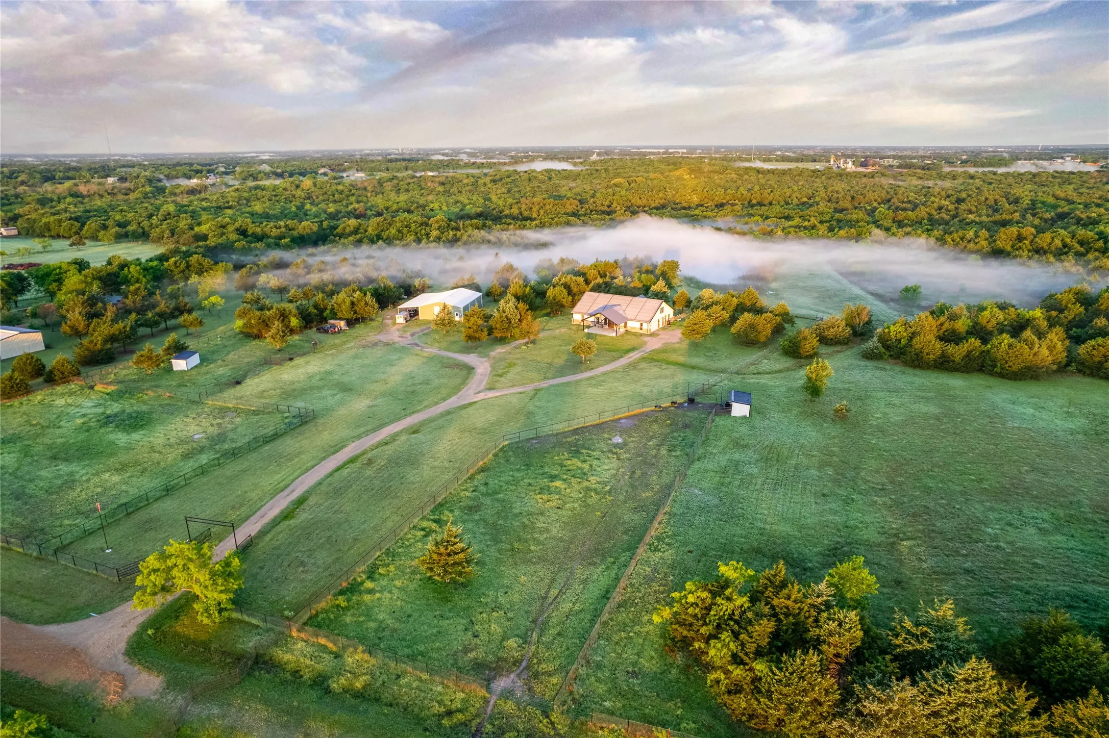 Expansive property featuring a main residence, two outbuildings, extensive green space, and mature trees