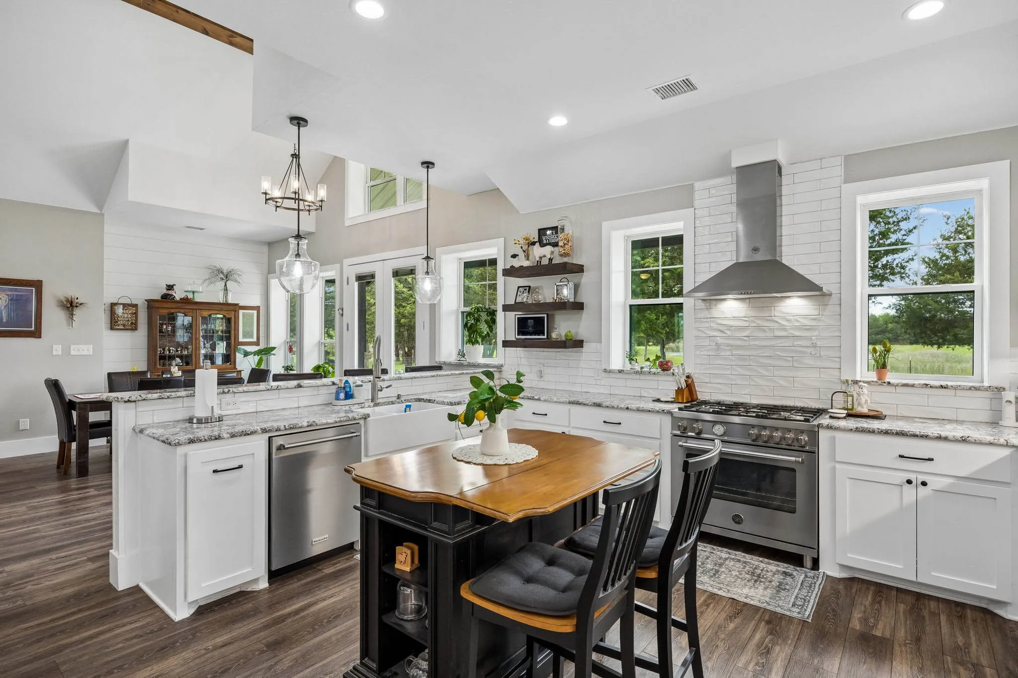 Spacious kitchen featuring an apron-front sink, stainless steel appliances, granite countertops, and white subway tile backsplash