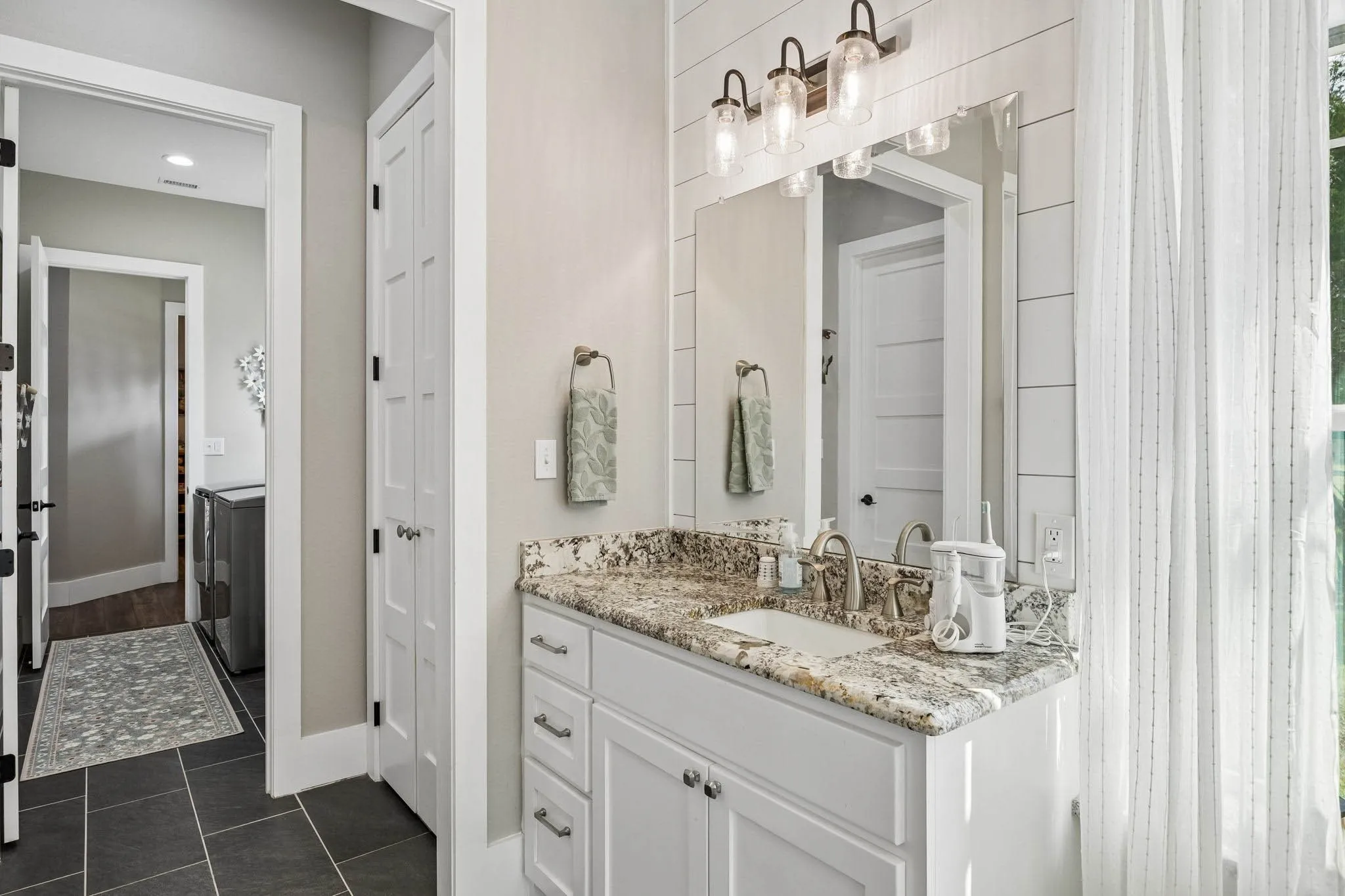 Bathroom vanity featuring a speckled countertop, undermount sink, and brushed nickel faucet