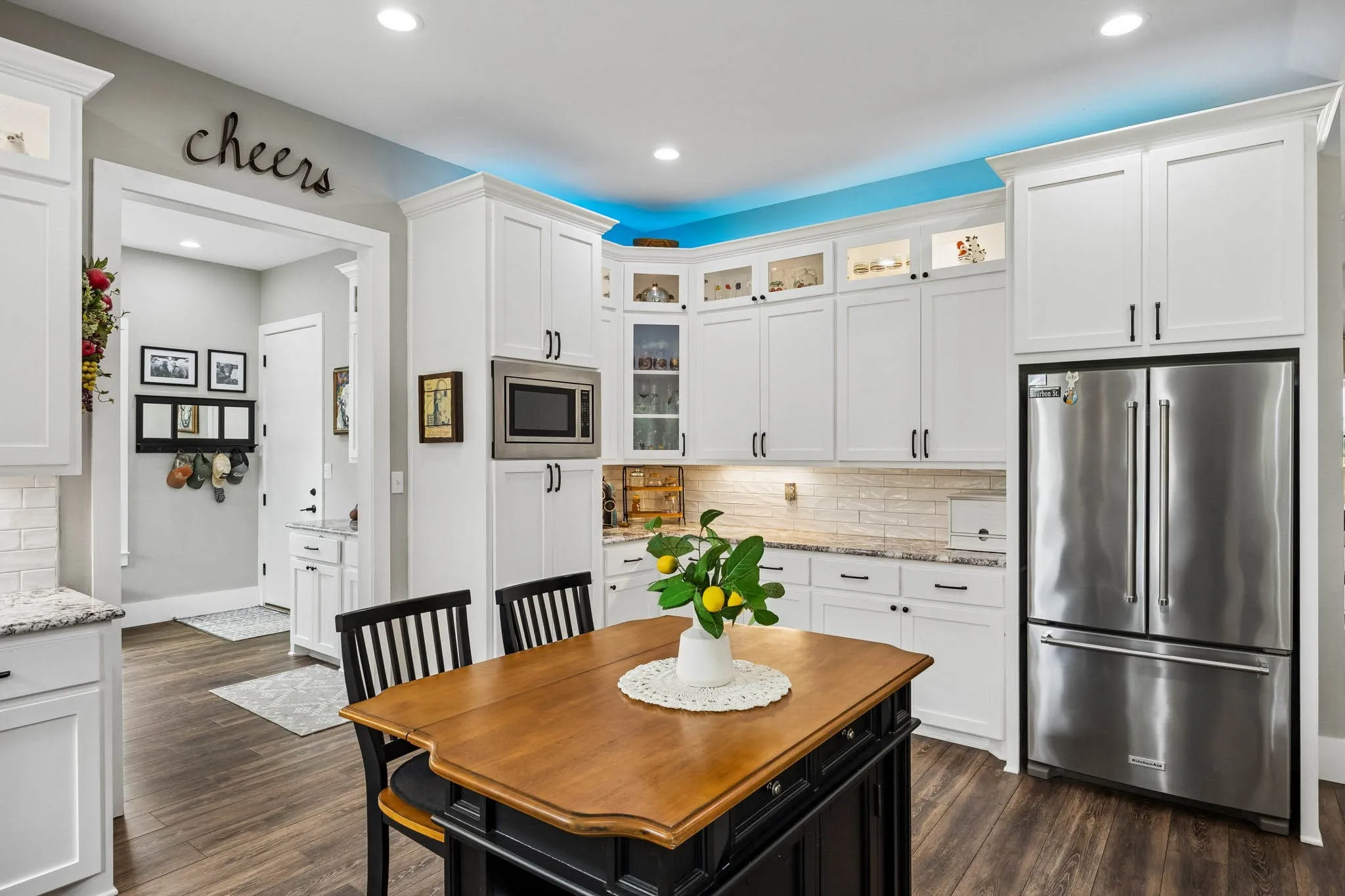 Kitchen featuring white cabinetry, stainless steel appliances, wood-finish flooring, a central island with seating, and recessed lighting