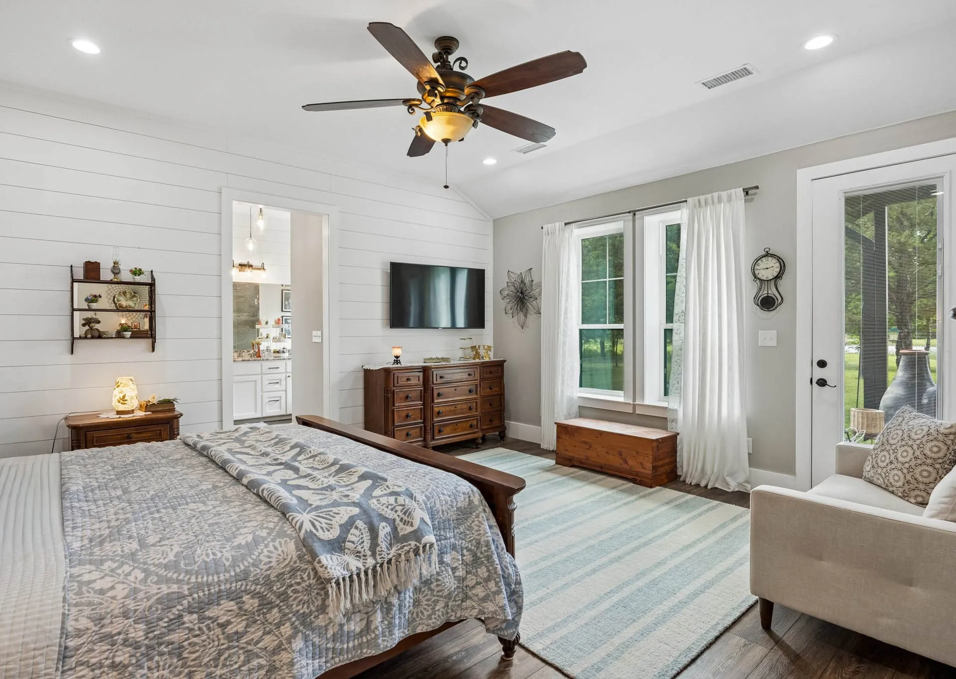 Spacious room featuring wood-finish flooring, white shiplap accent walls, a ceiling fan with integrated lighting, recessed lighting, and a glass-paneled exterior door