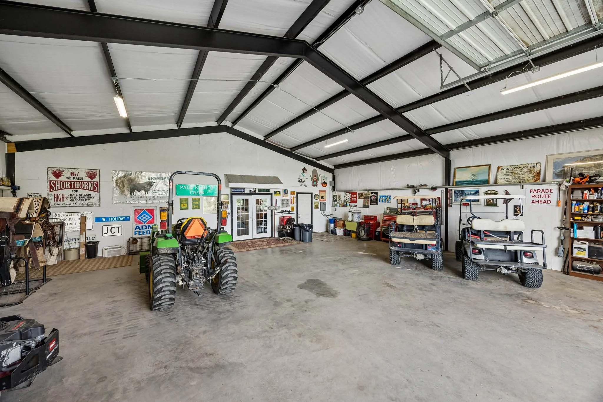 Spacious interior featuring a concrete floor, exposed metal beam ceiling, and fluorescent lighting