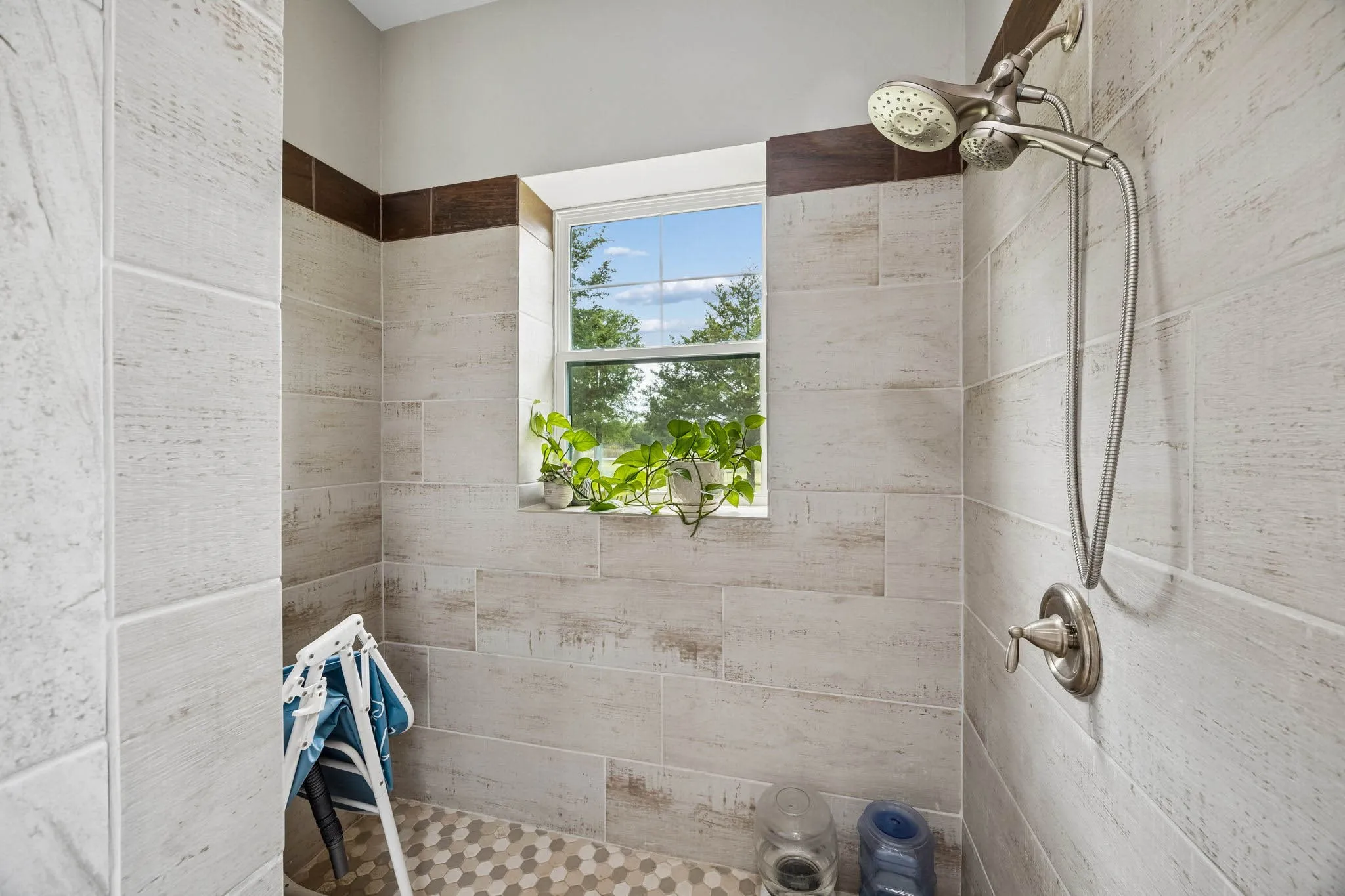 Walk-in shower with wood-look tile walls, an accent tile band, and a hexagonal tile floor