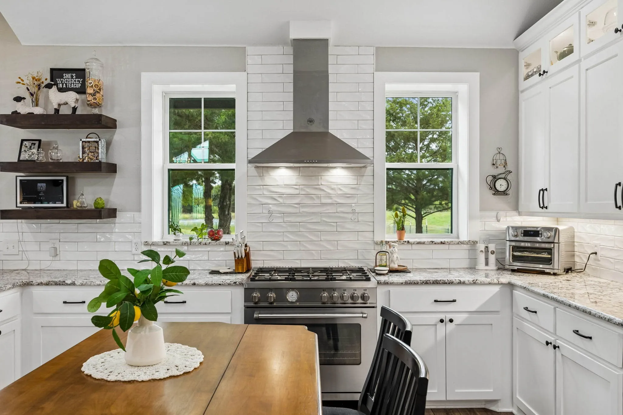 Modern kitchen featuring white cabinetry, granite countertops, a stainless steel range with matching hood, and textured subway tile backsplash