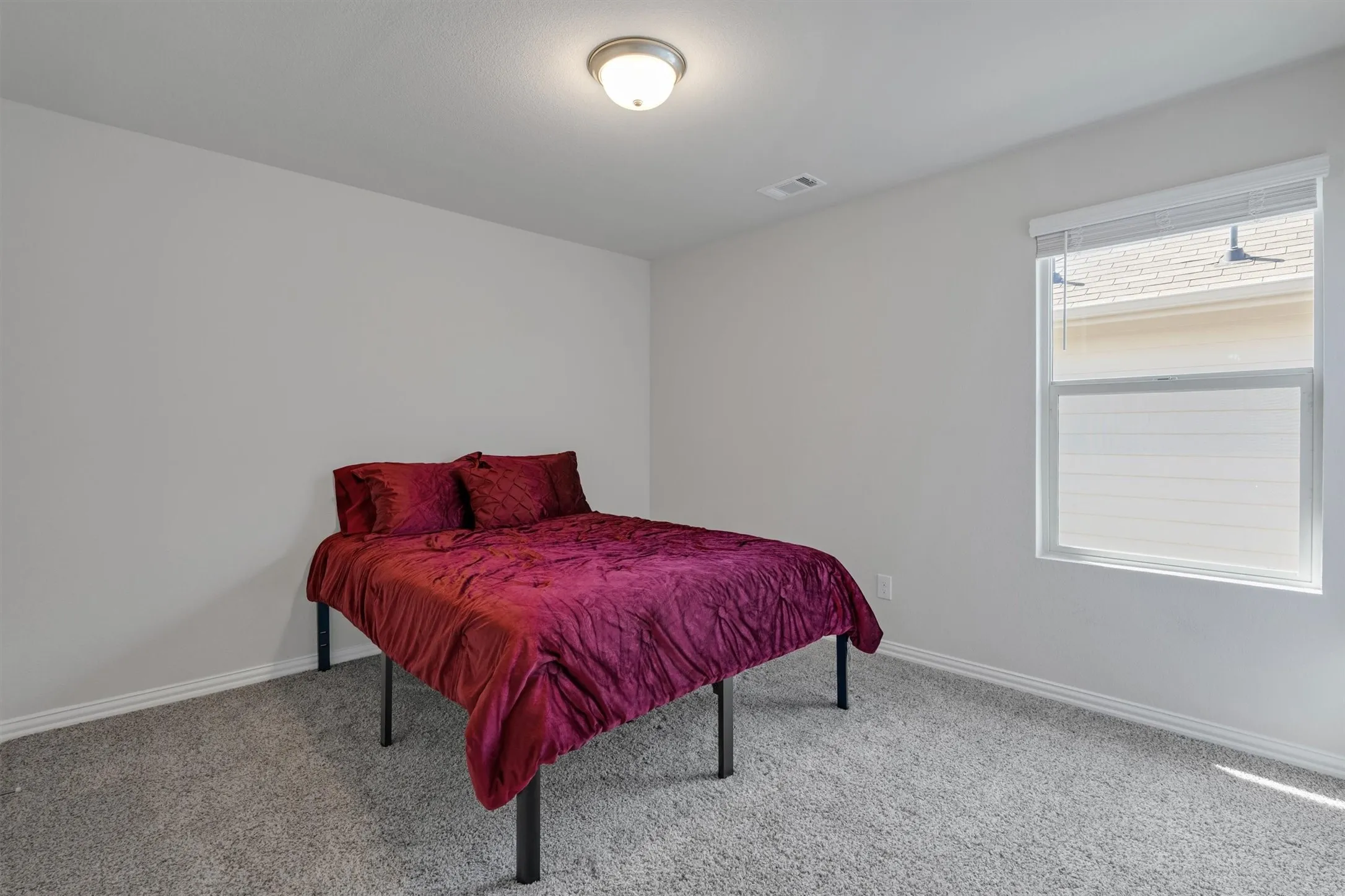 Neutral wall color, wall-to-wall carpeting, white baseboards, and a single window with blinds