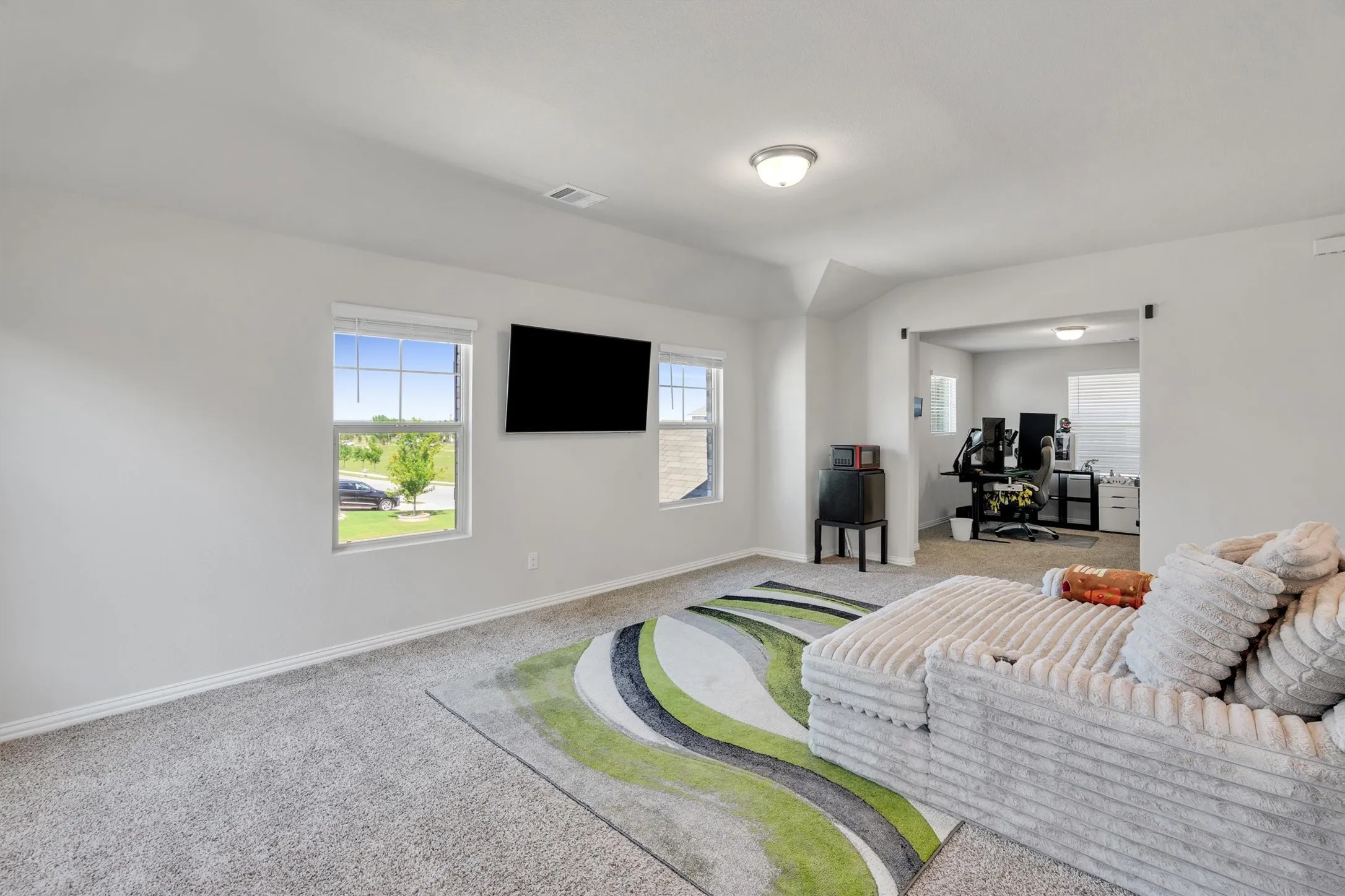 Expansive carpeted room featuring white walls and multiple windows