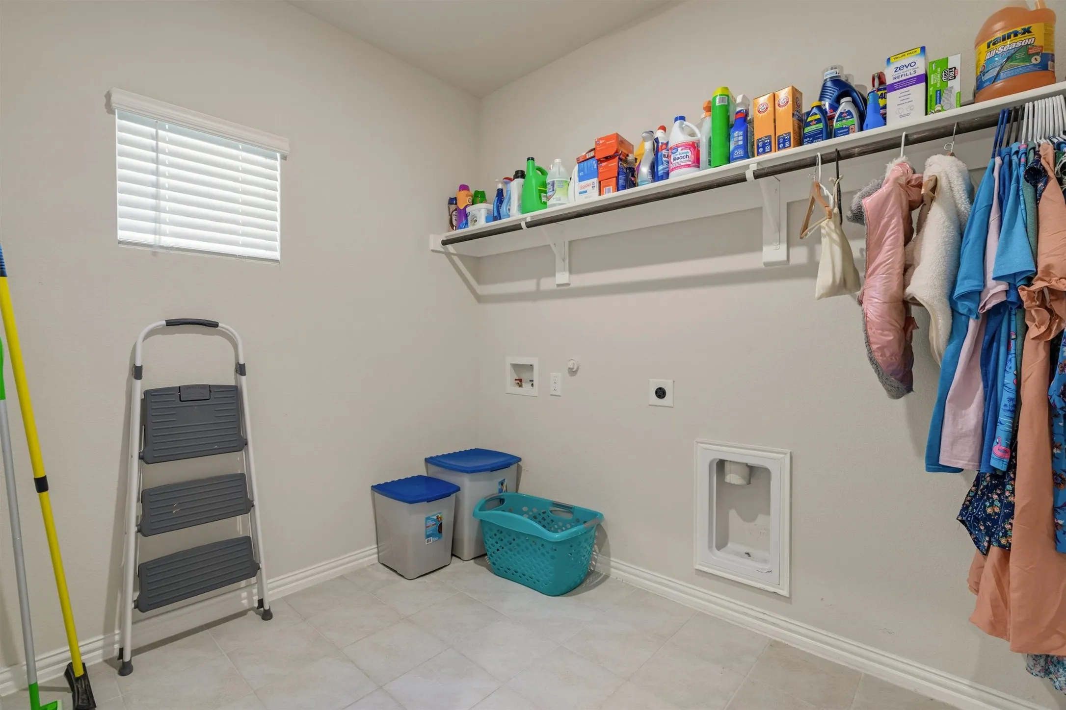 Laundry room featuring a window with blinds, tile flooring, and light-toned walls