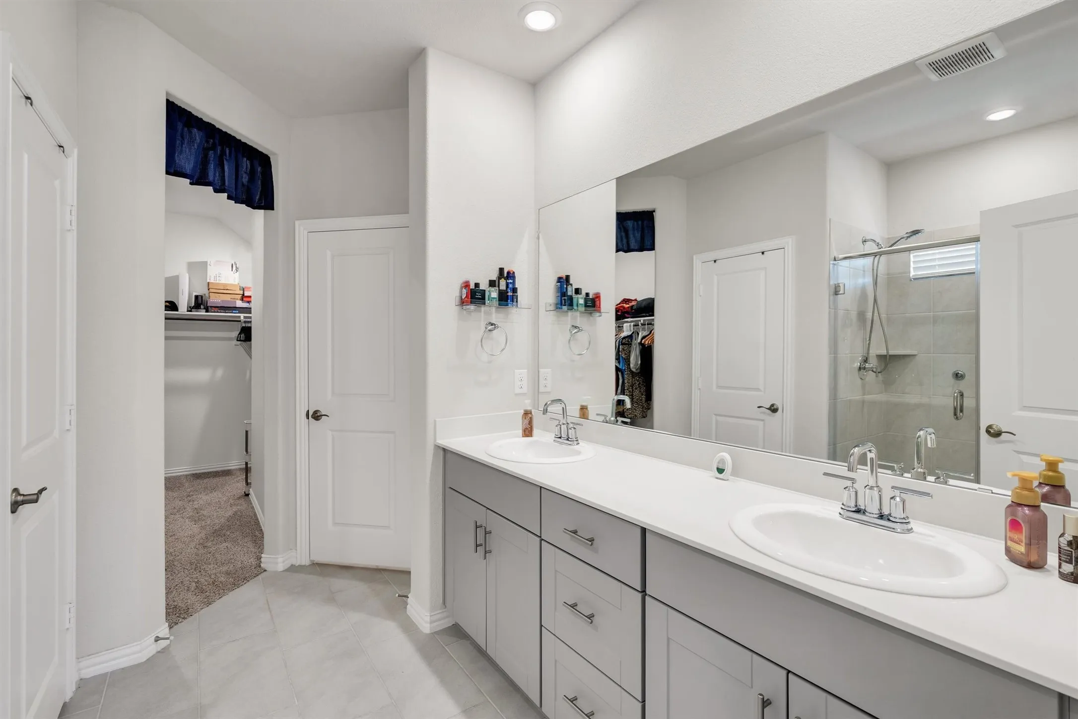 Dual vanity featuring light gray cabinetry, white countertops, and chrome fixtures