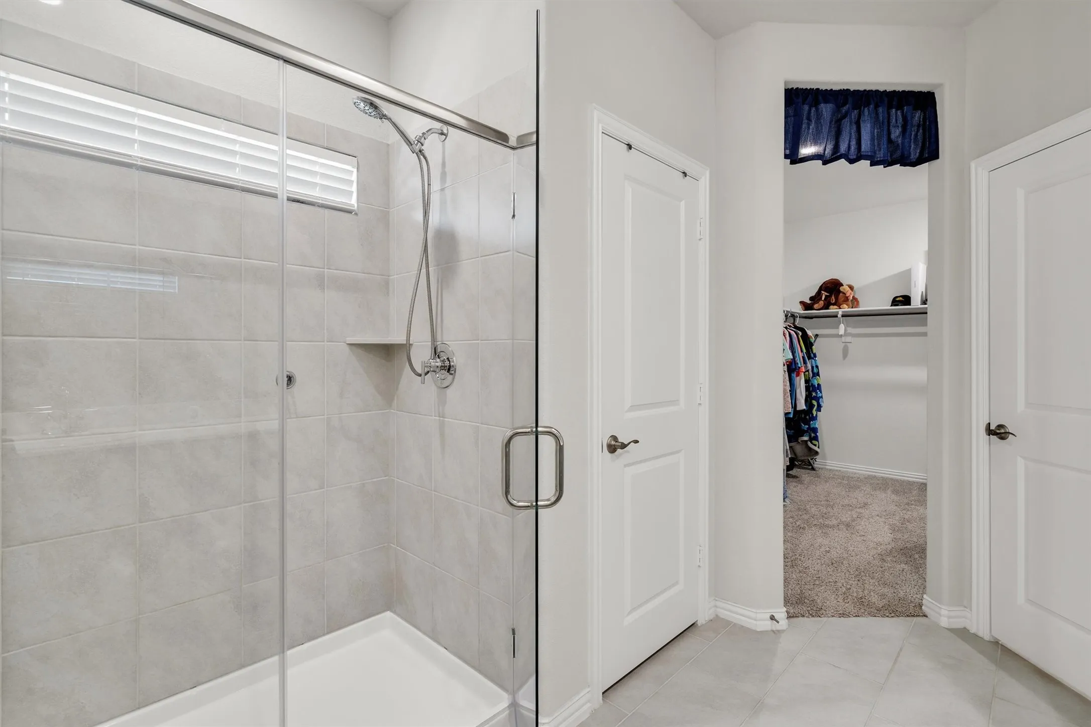 Walk-in shower featuring a glass enclosure, tiled walls, and a built-in shower niche
