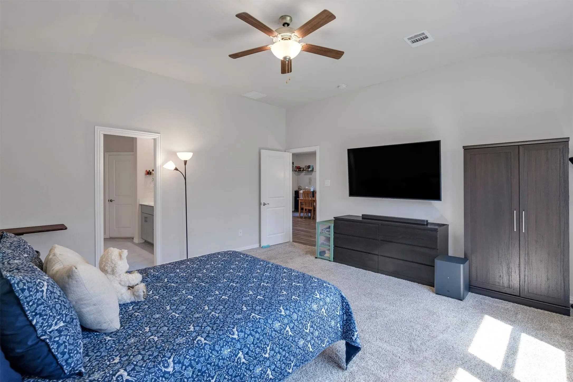 Spacious bedroom featuring light neutral walls and soft carpet flooring