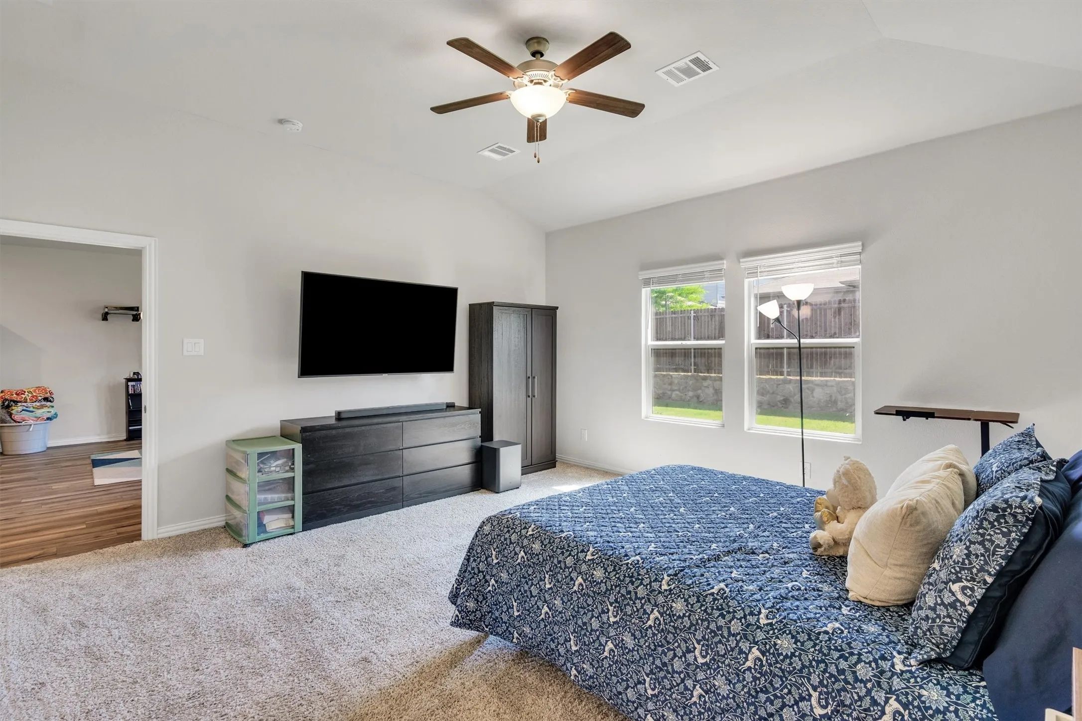 Carpeted room featuring a vaulted ceiling with a ceiling fan and two windows