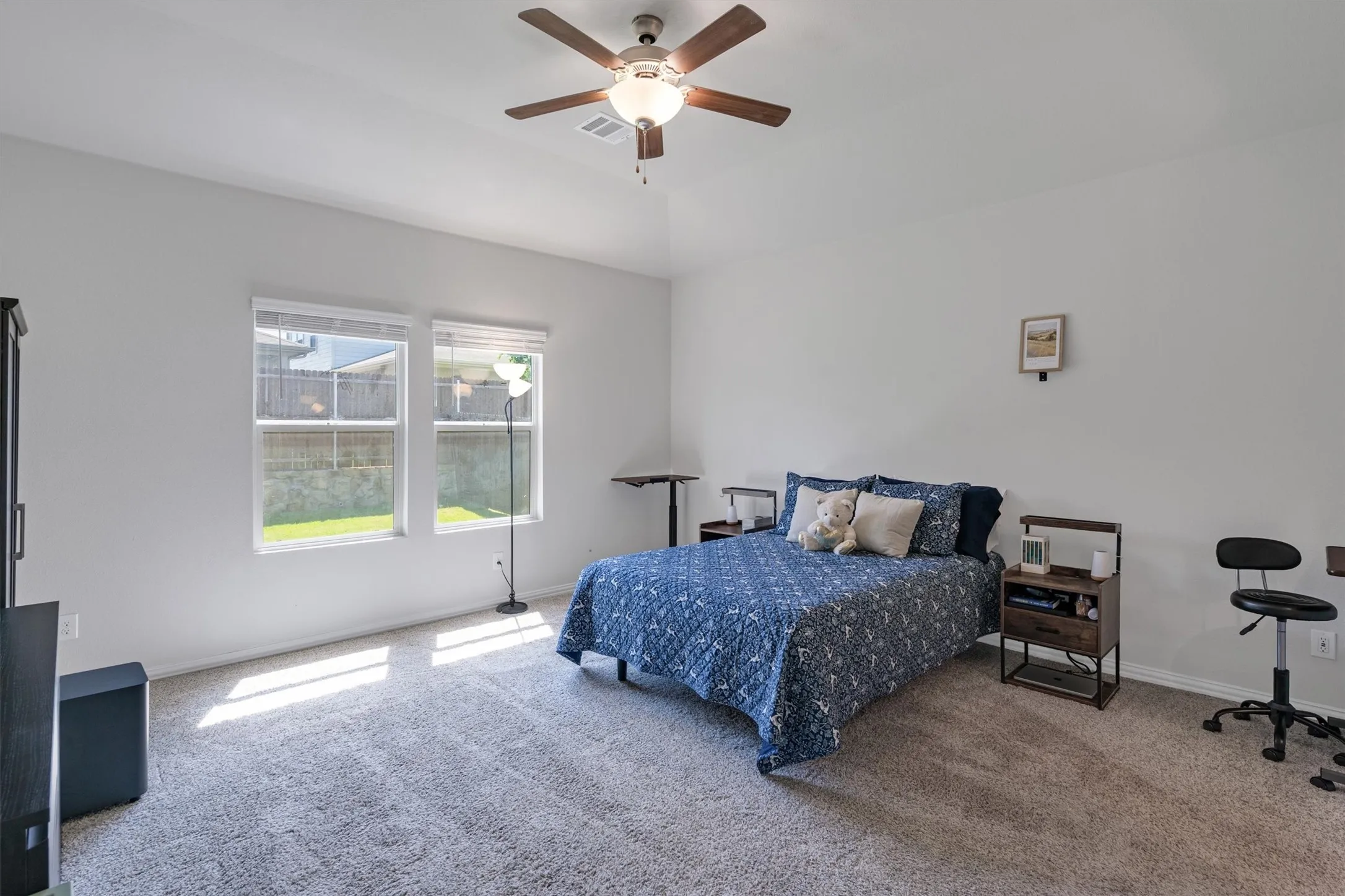 Carpeted room featuring dual windows with blinds, a ceiling fan with integrated lighting, and white wall finishes