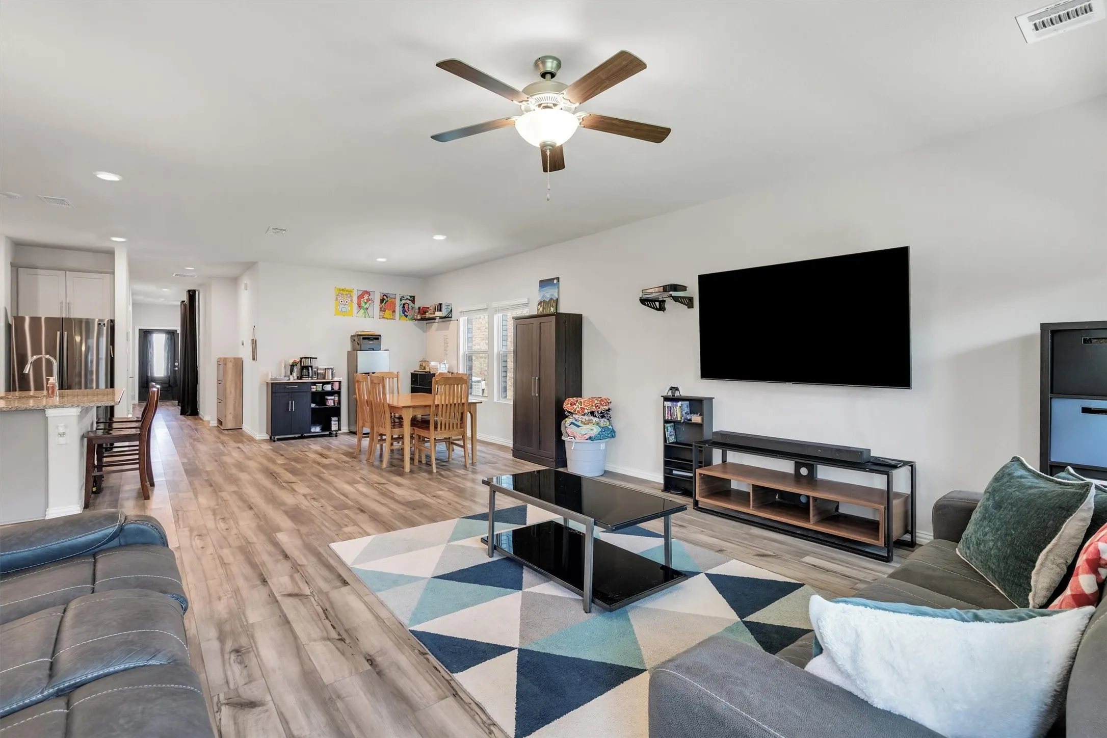 Open-concept living area featuring wood-finish flooring, recessed lighting, and a ceiling fan