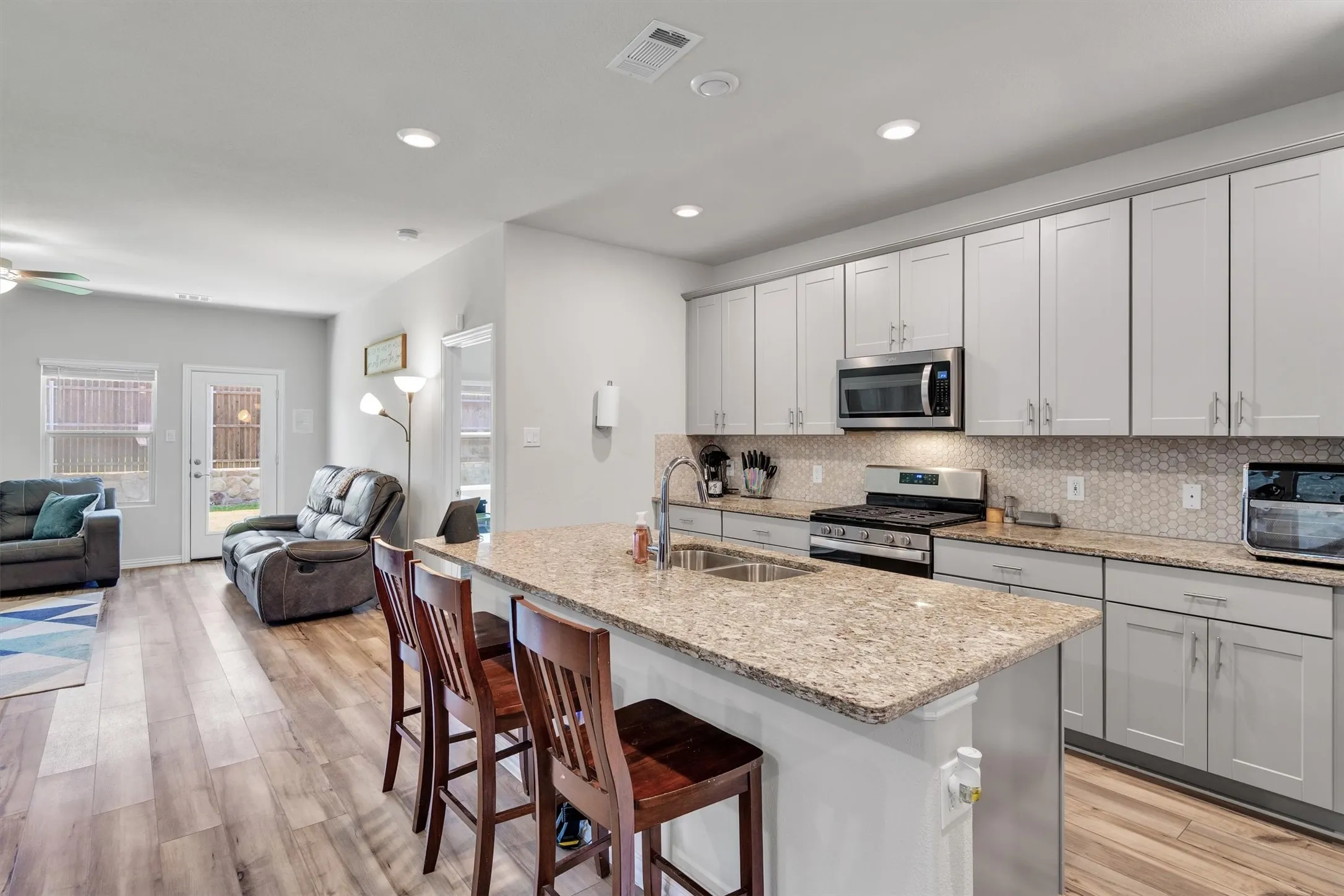 Open-concept kitchen featuring an island with a double basin sink and a granite countertop