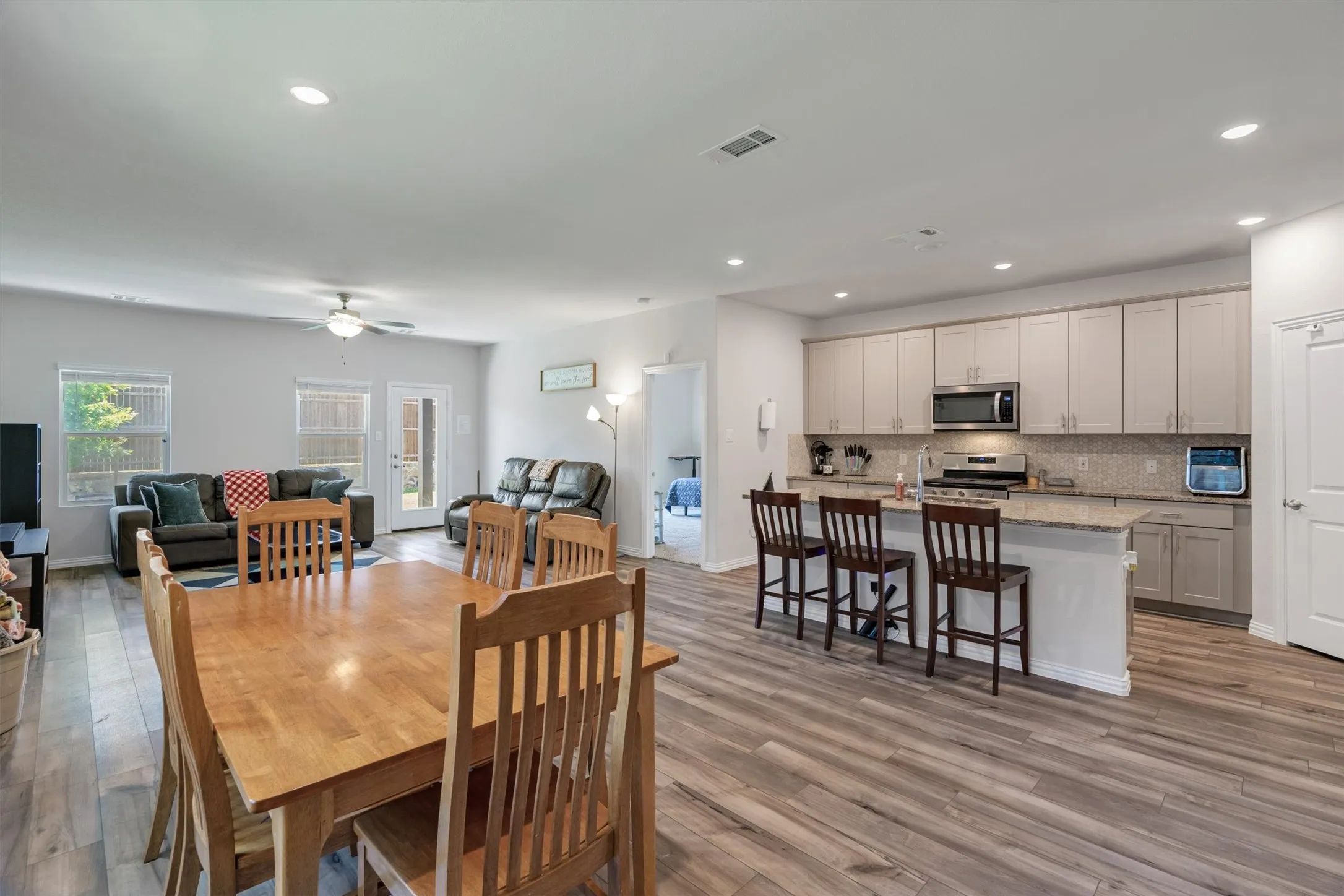 Open-concept living space featuring wood-finish flooring, recessed lighting, and a neutral color palette