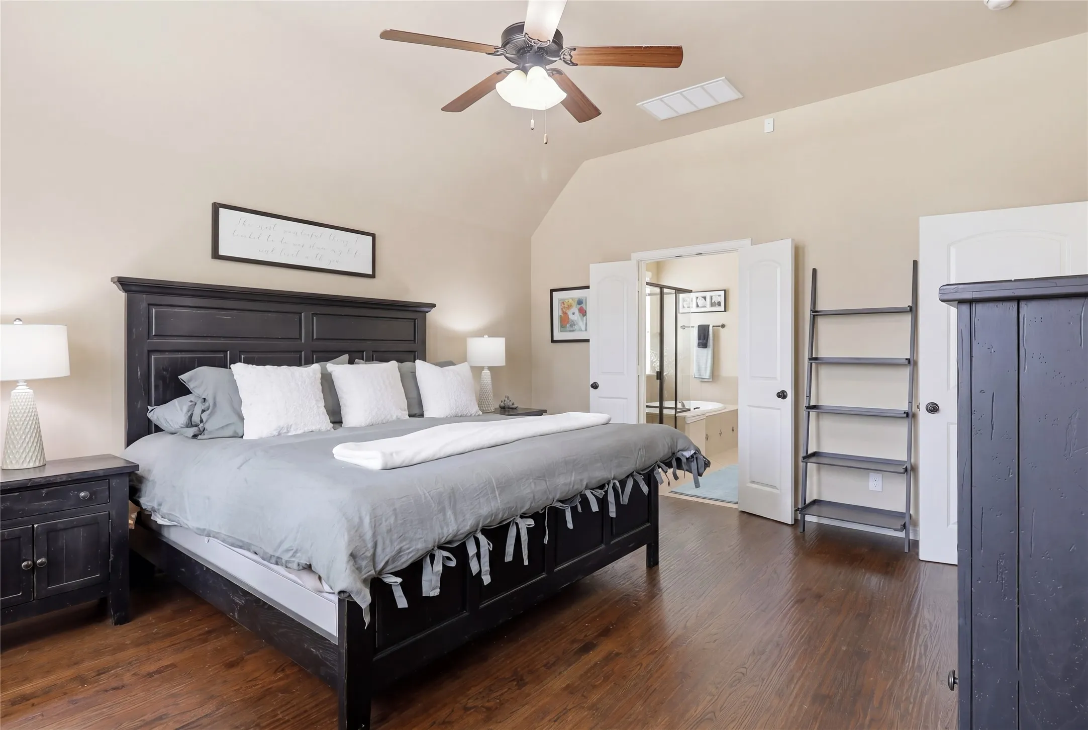 Spacious bedroom featuring wood-finish flooring, vaulted ceilings, and a ceiling fan