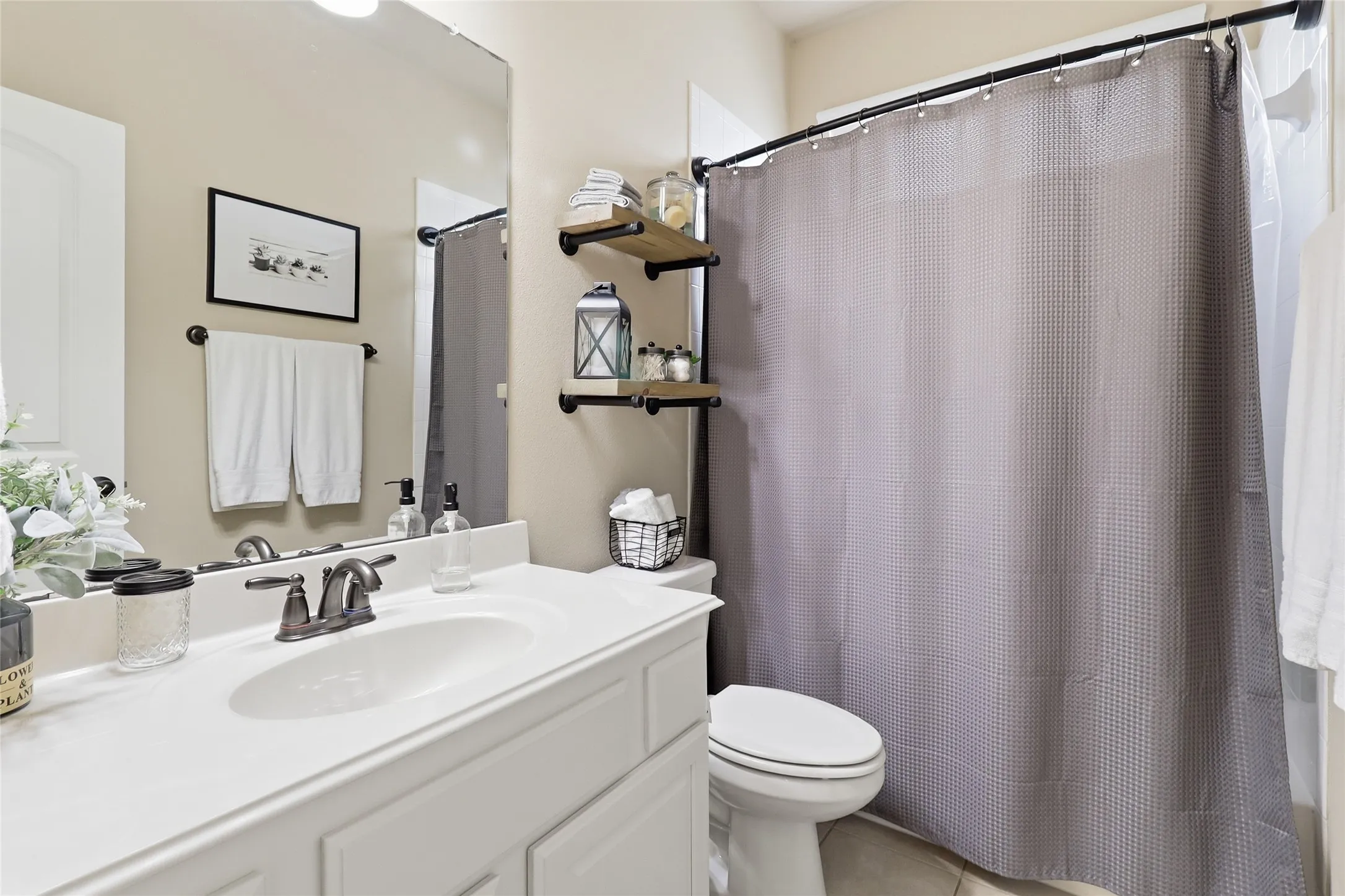 Bathroom featuring a white vanity with an integrated sink, brushed bronze faucet, and a large wall-mounted mirror