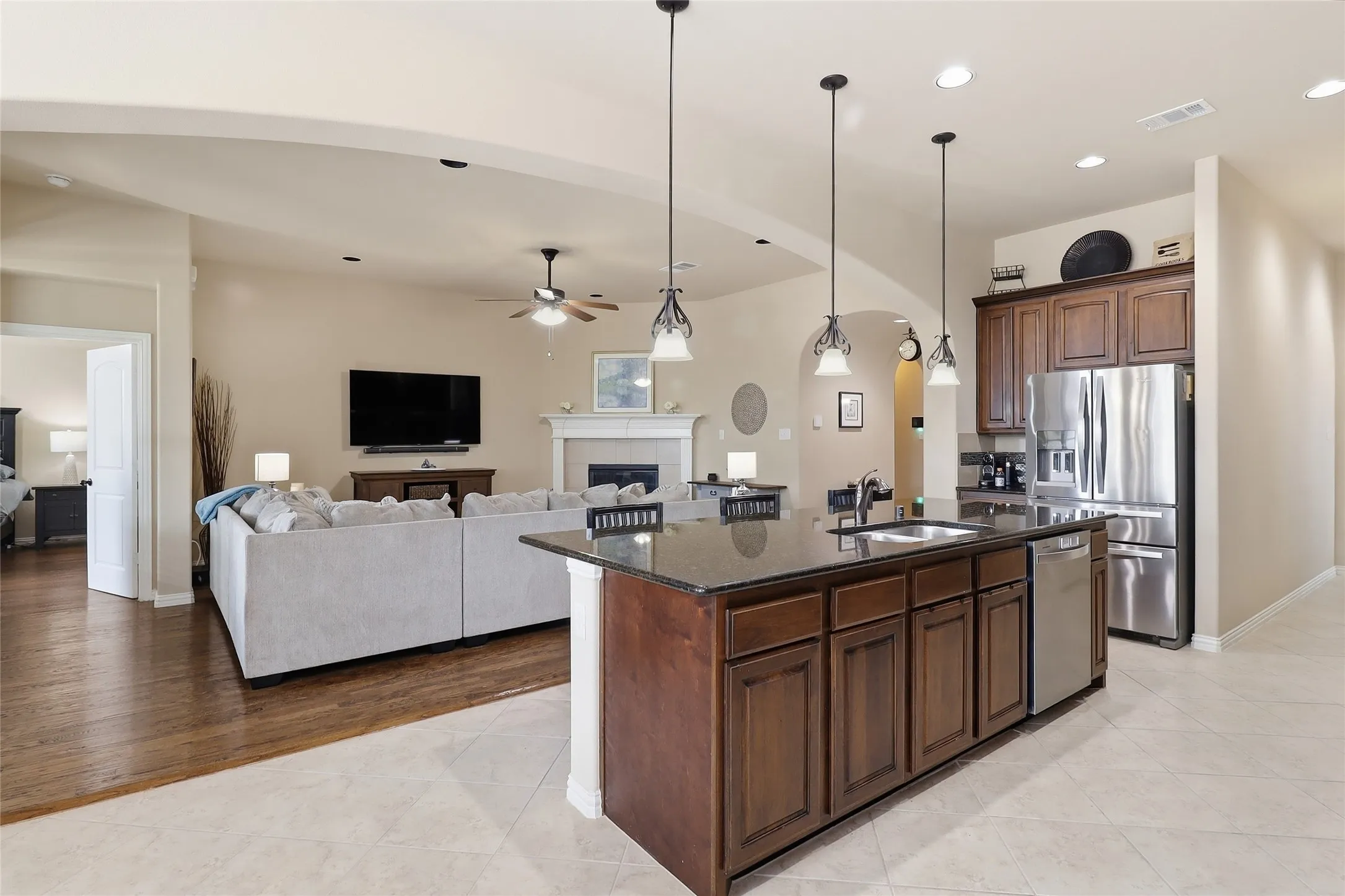 Kitchen with dark wood cabinetry, stainless steel appliances, and a central island featuring a sink and pendant lighting