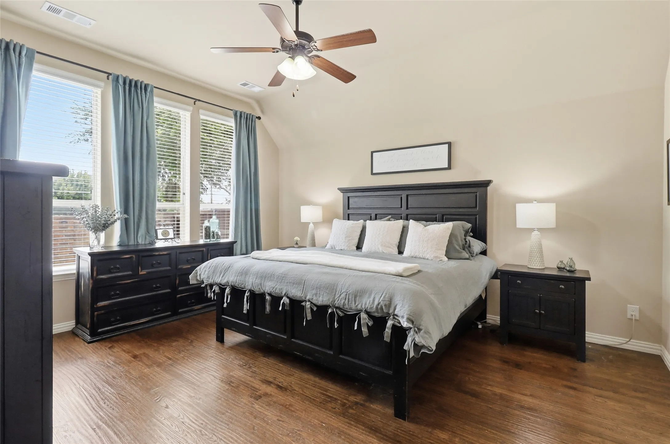 Spacious room featuring wood-finish flooring, light tan walls, and a ceiling fan with integrated lighting