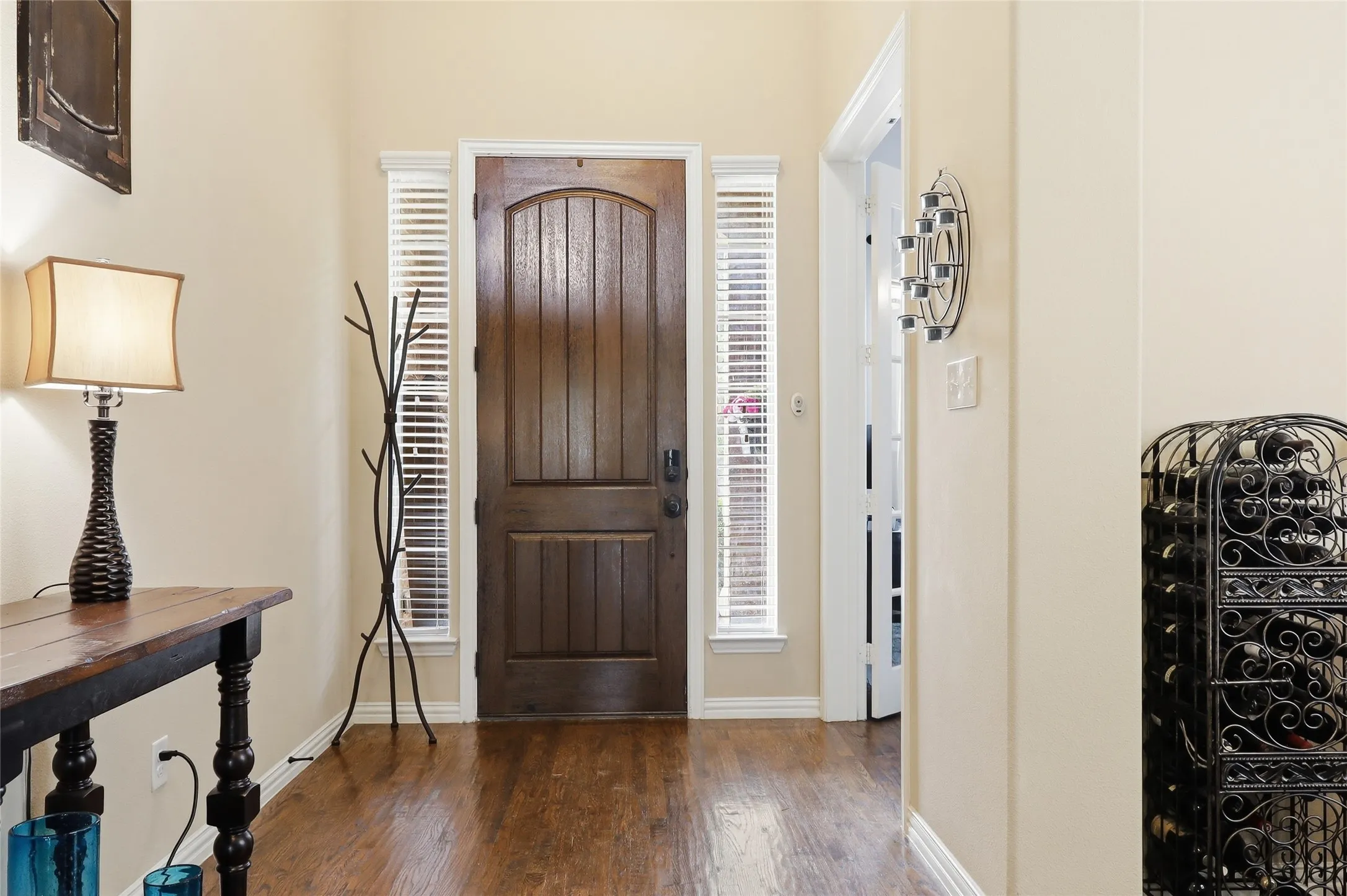 Front entry featuring a solid wood arched door with sidelight windows, wood-finish flooring, and neutral wall tones