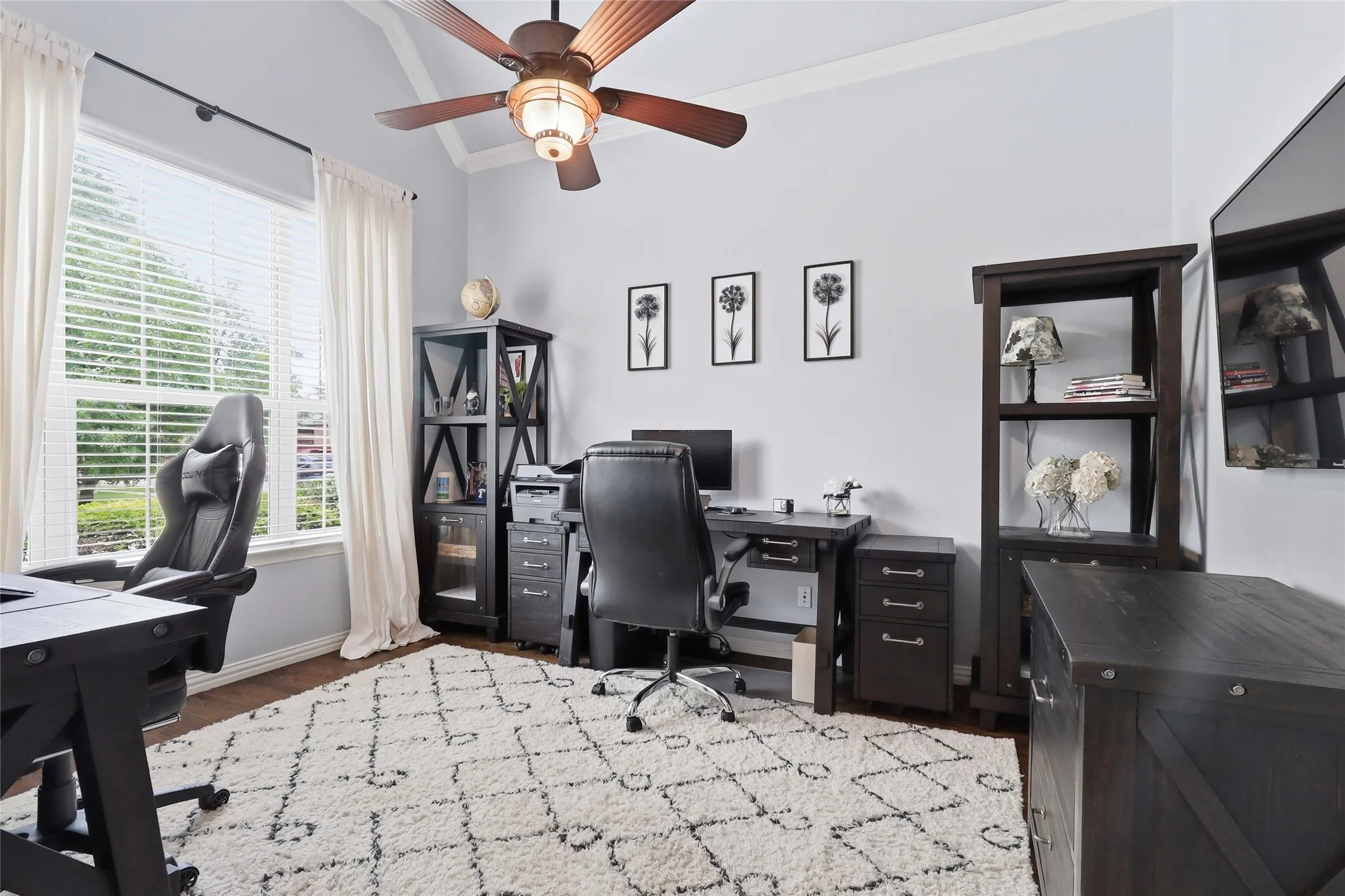 Spacious room featuring vaulted ceilings, a prominent window with blinds and drapes, and wood-finish flooring