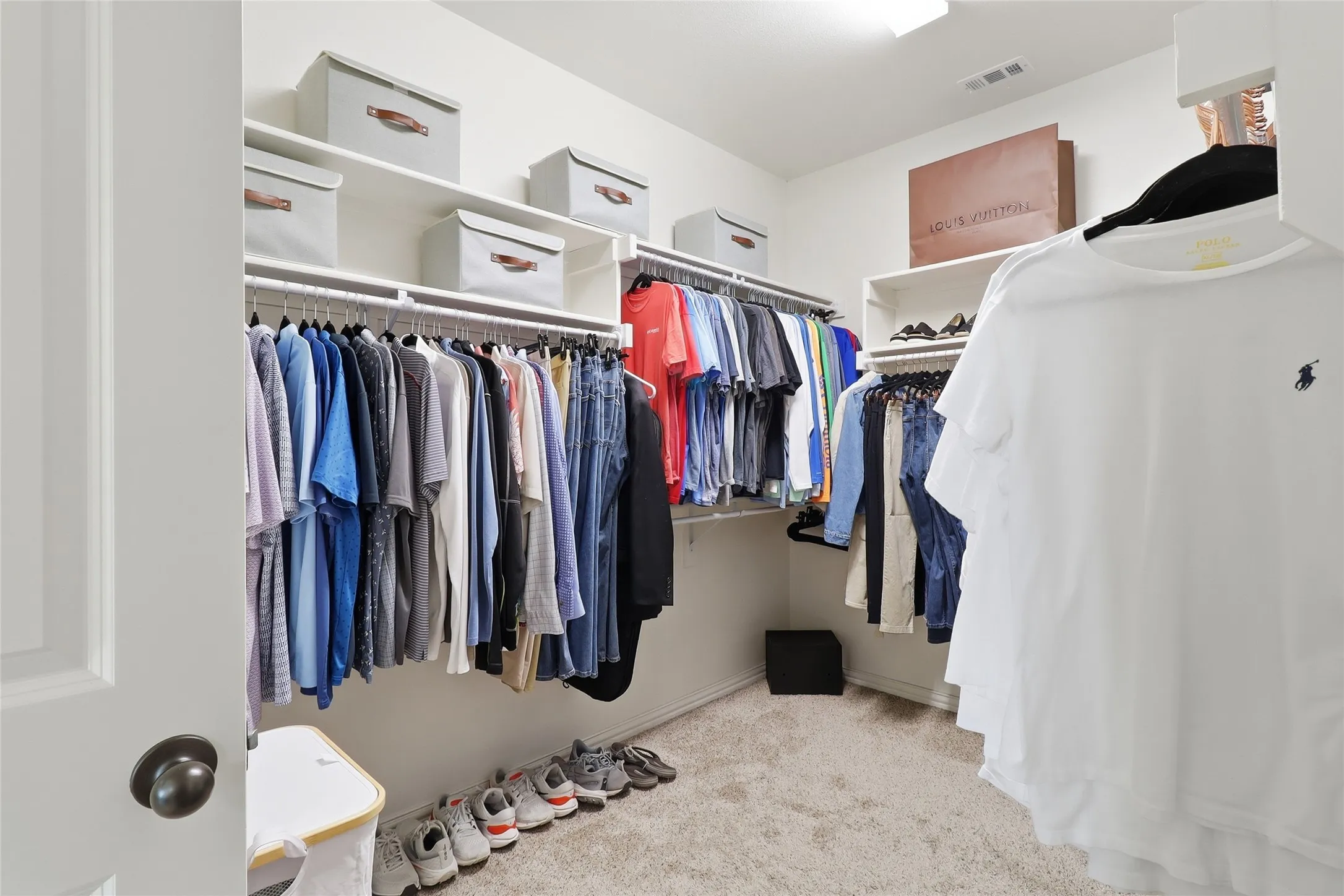 Walk-in closet with carpet flooring, extensive shelving, and multiple hanging rods for organization