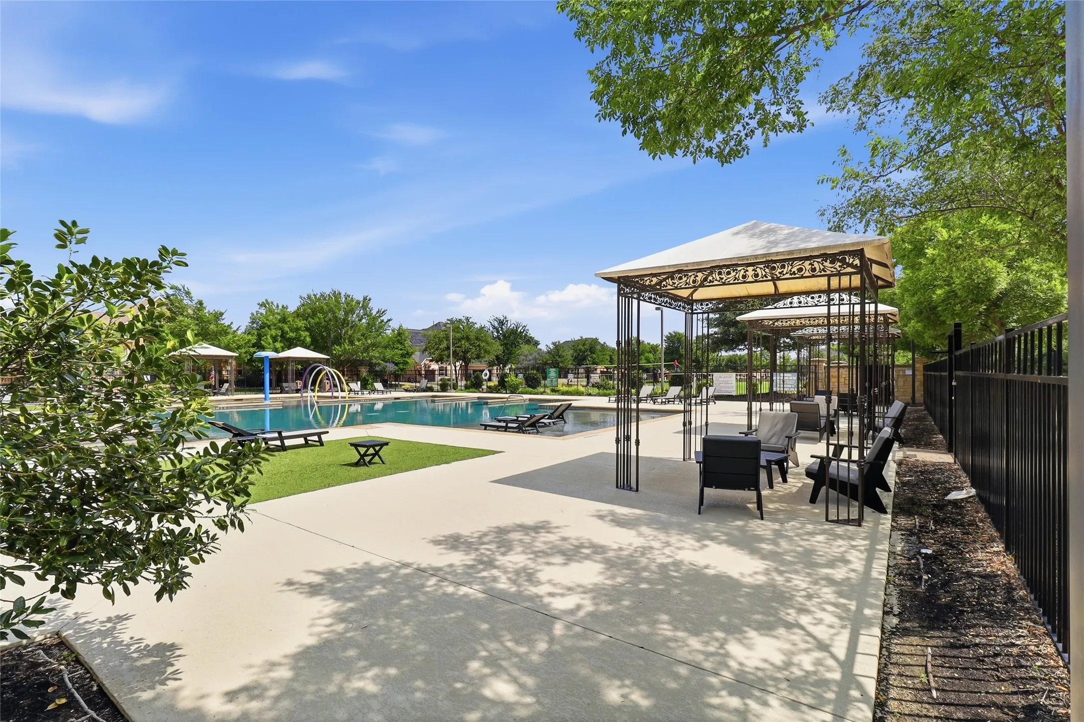 Outdoor swimming area featuring multiple cabanas with seating, a large swimming pool, and dedicated lounging spaces with artificial turf accents