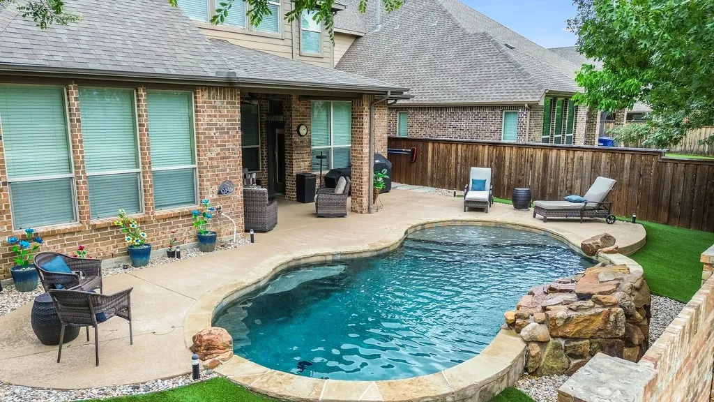 Backyard featuring a freeform swimming pool with a stone waterfall feature