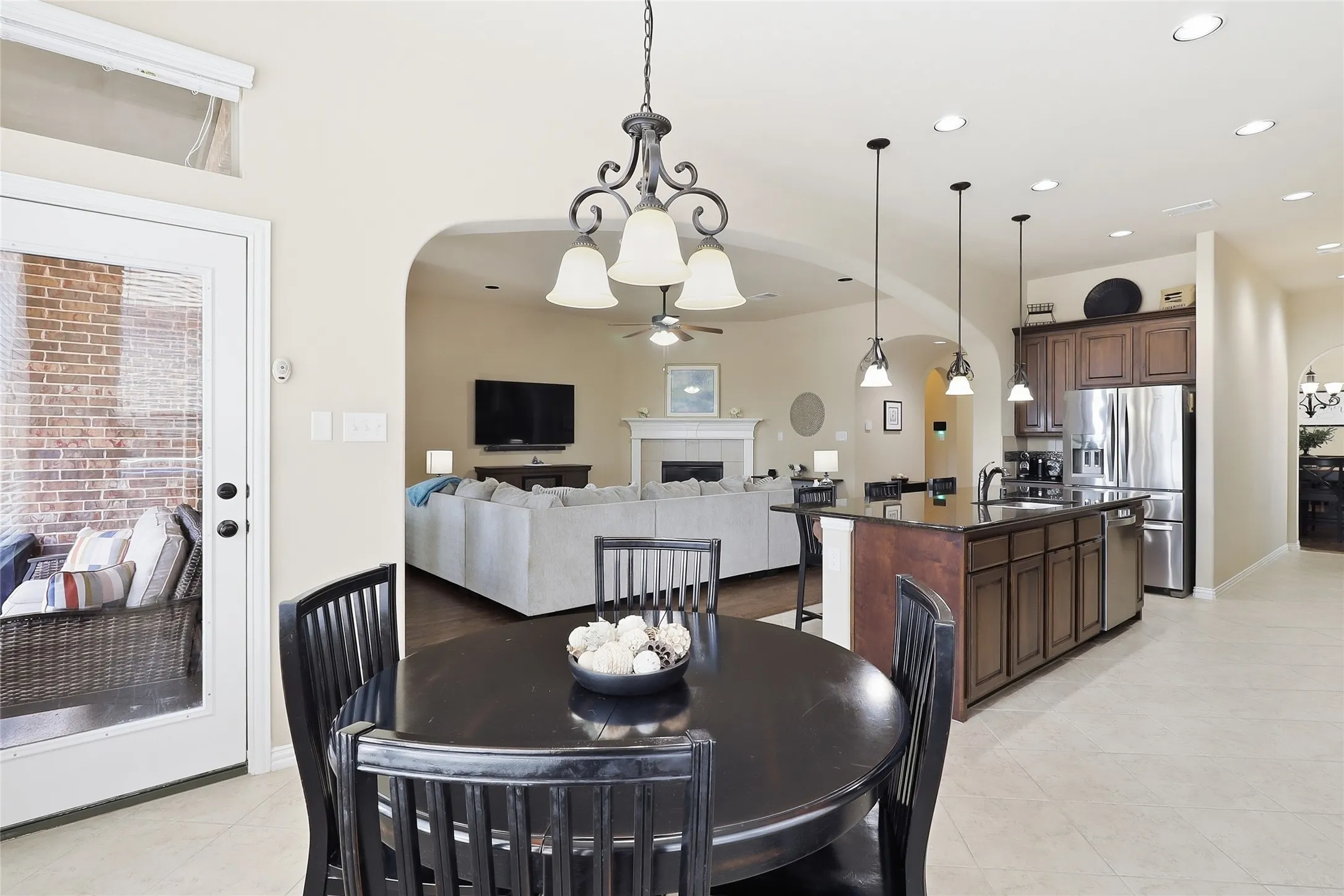 Open-concept living area with a kitchen island, pendant lighting, stainless steel appliances, and a dining area featuring a chandelier