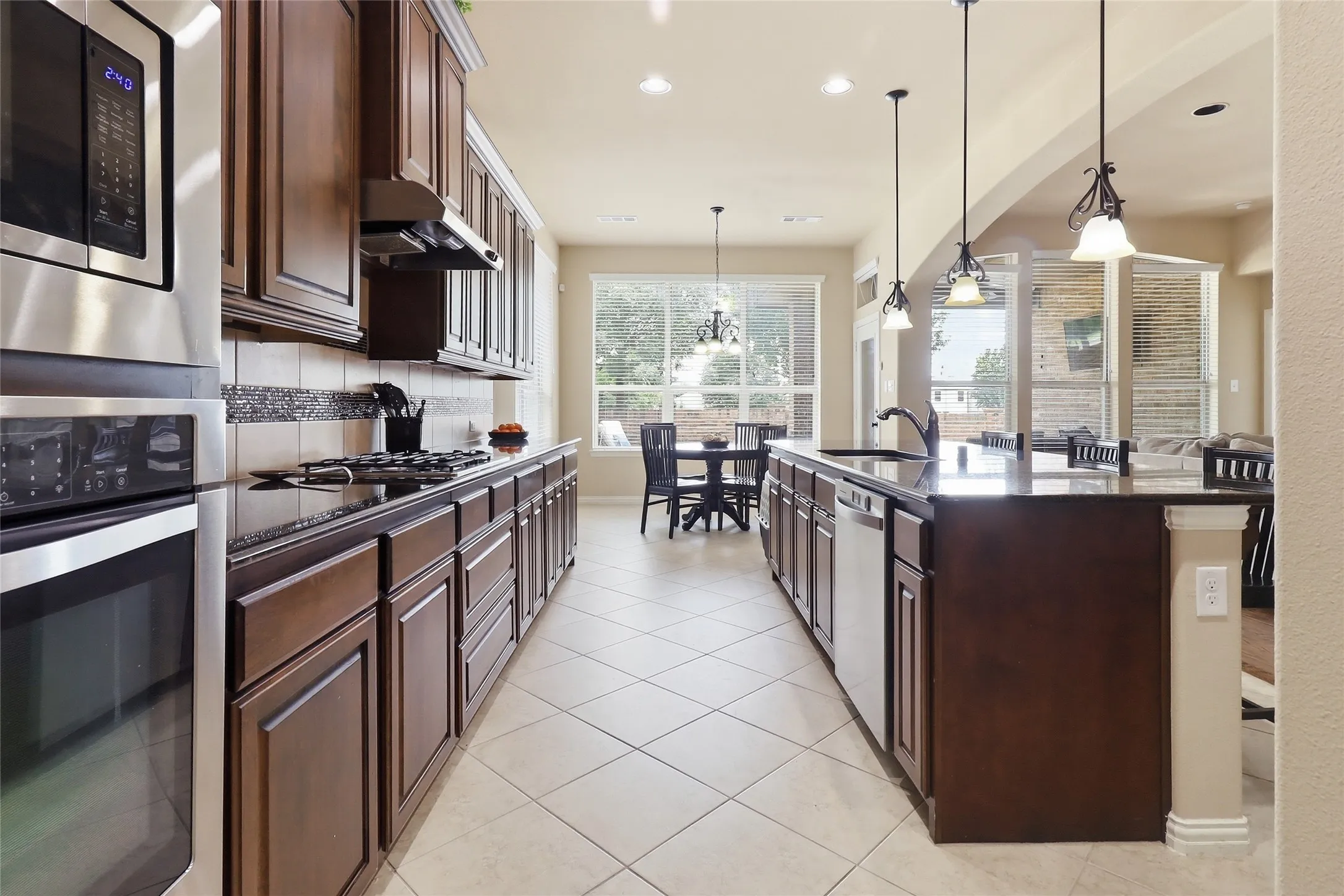 Kitchen featuring dark wood cabinetry, black countertops, stainless steel appliances, and tile flooring